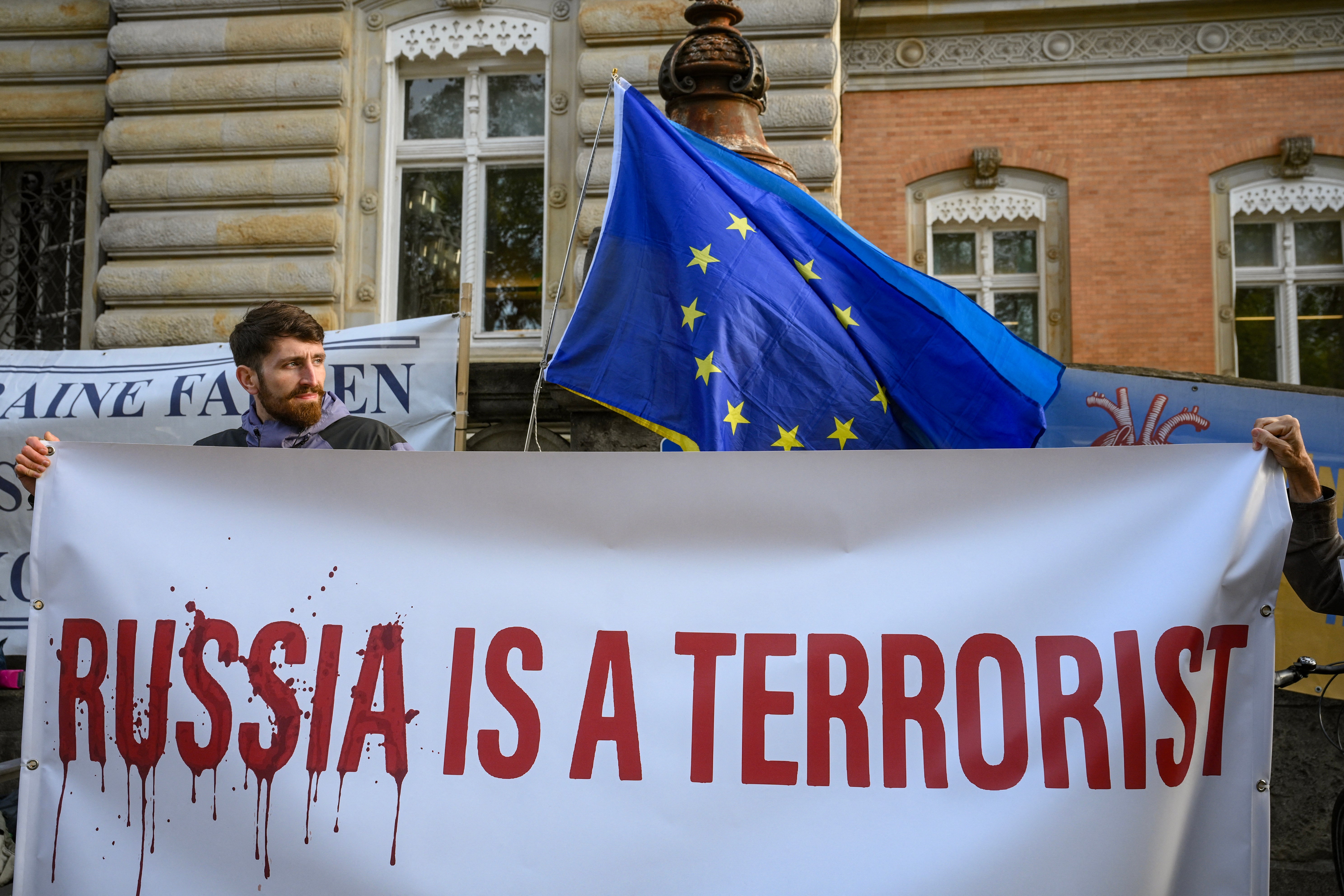 Pro-Ukrainian protestors holds a banner reading, ‘Russia is a terrorist’ outside the criminal justice building in Hamburg, northern Germany