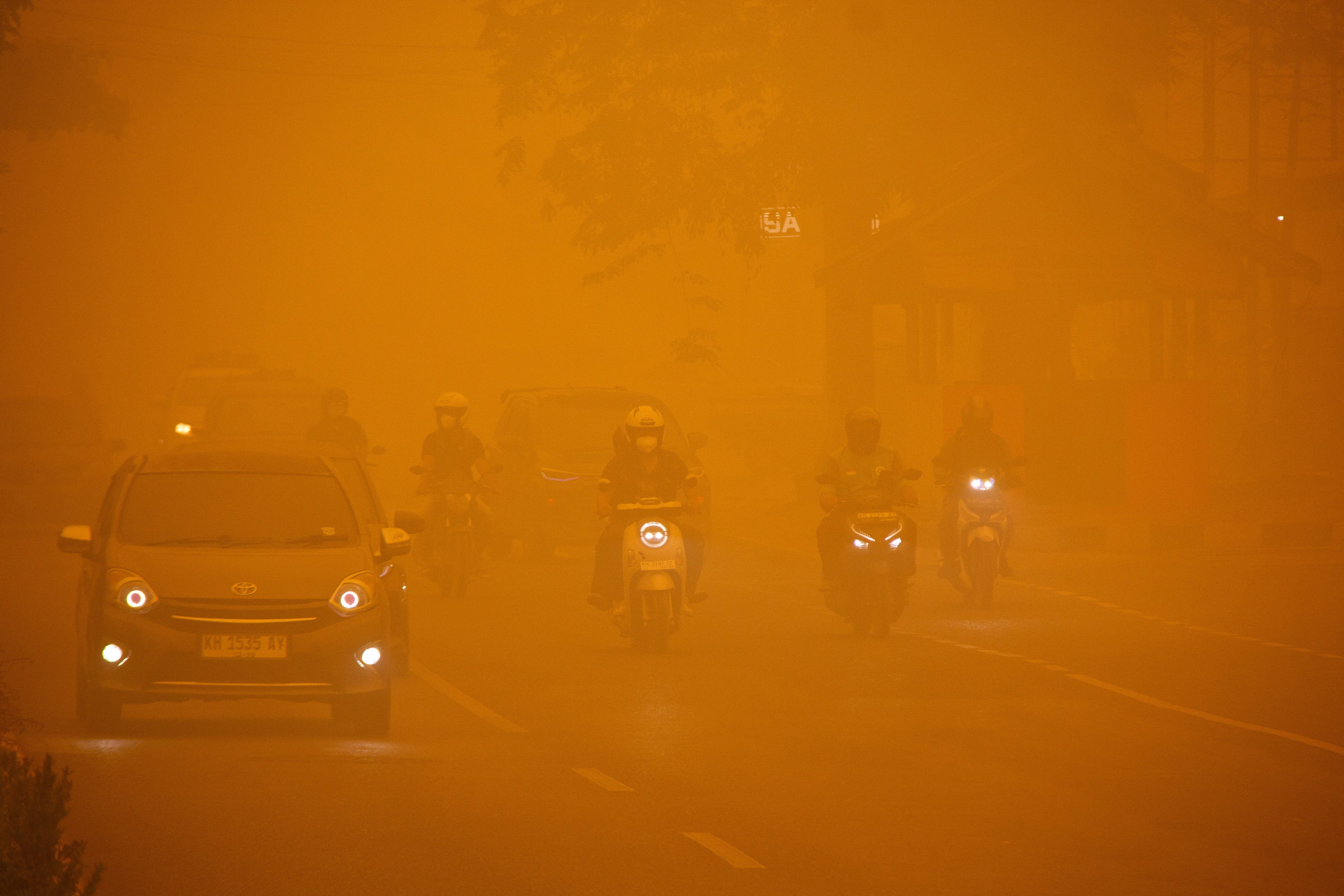 Motorists drive through a main road as haze from wildfires shrouds the area in Palangka Raya, Central Kalimantan province, Indonesia, October 14, 2026.