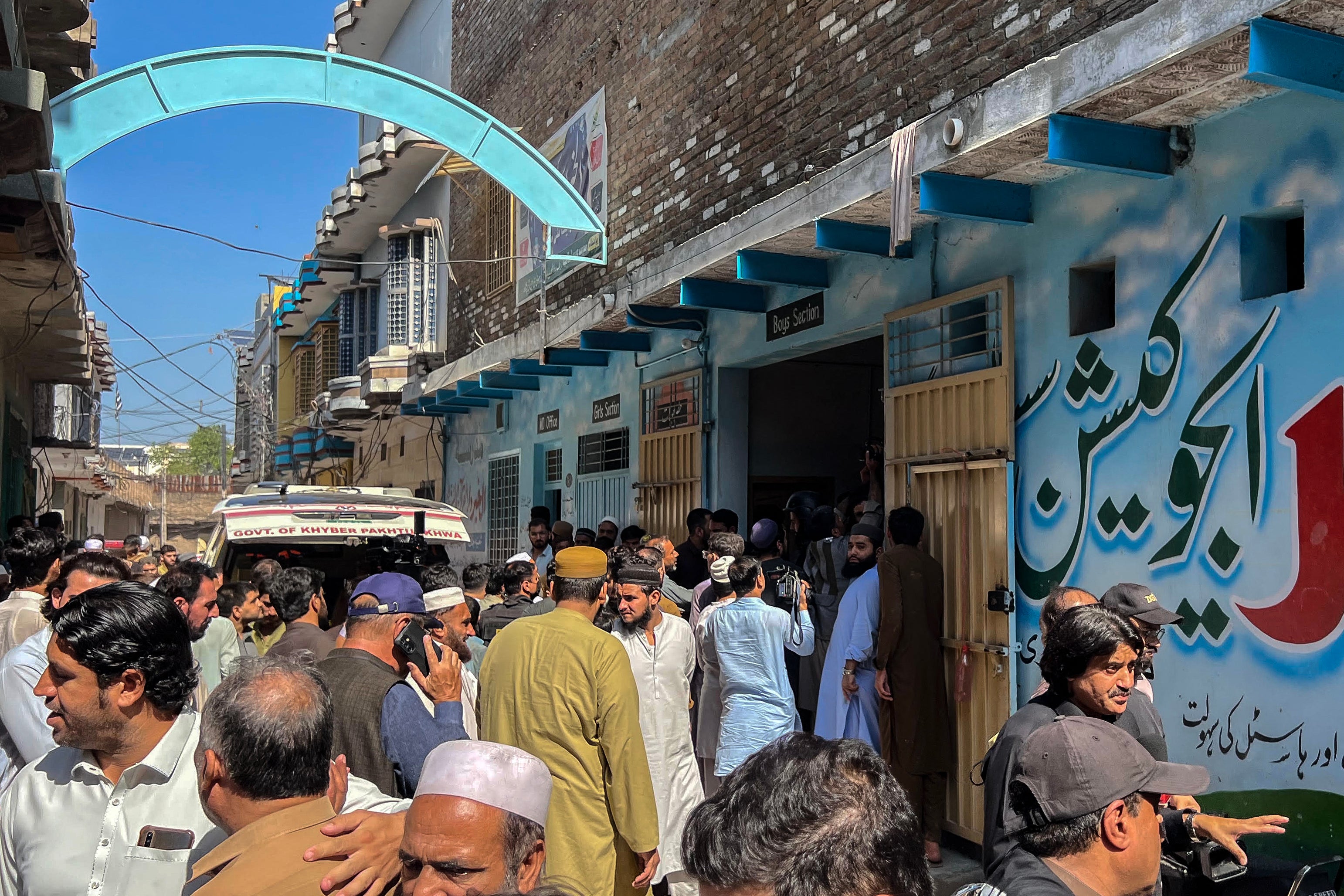 Residents gather during a search operation after a roof collapsed at a school in Peshawar