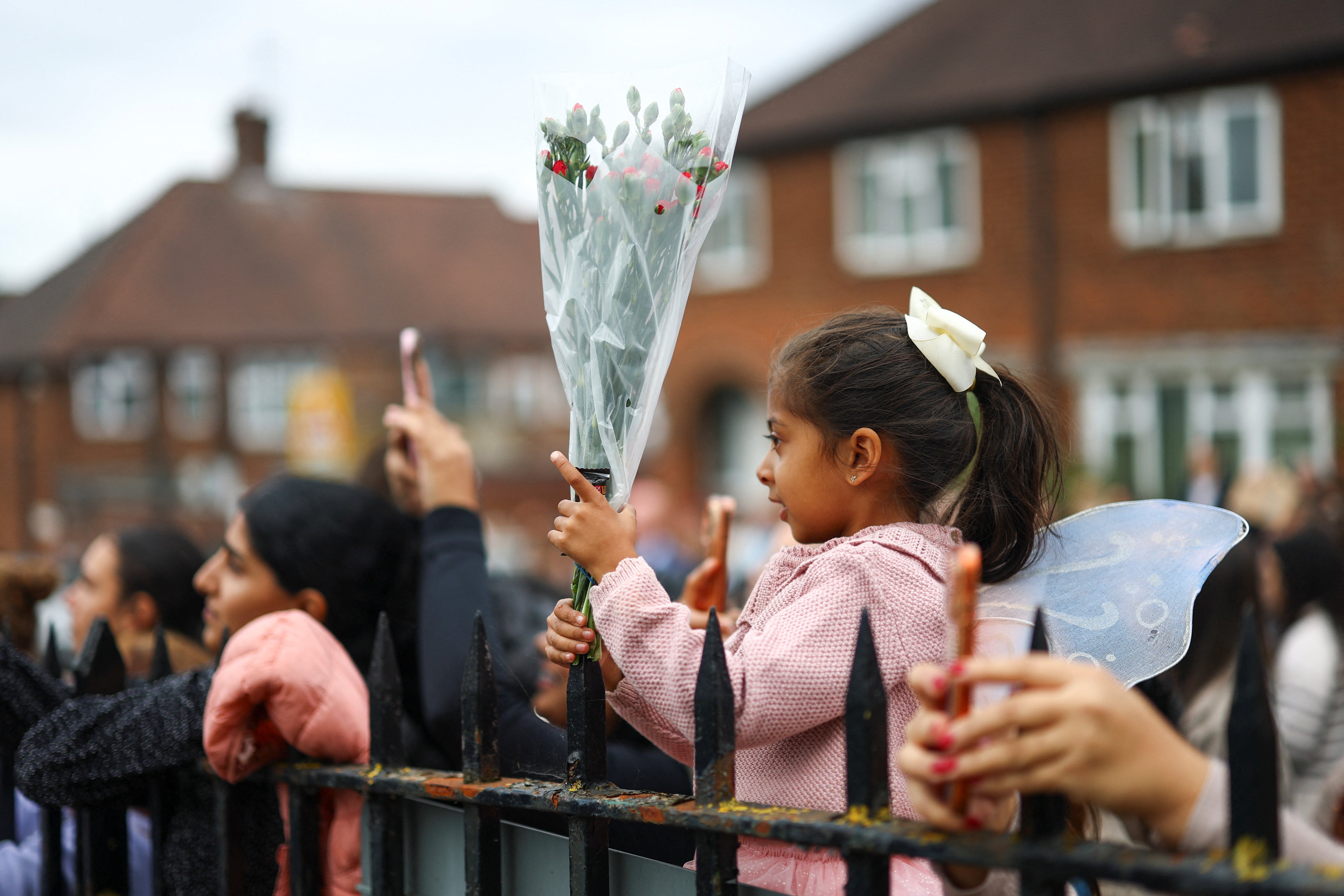 A girl holds flowers for Prince Harry and Meghan