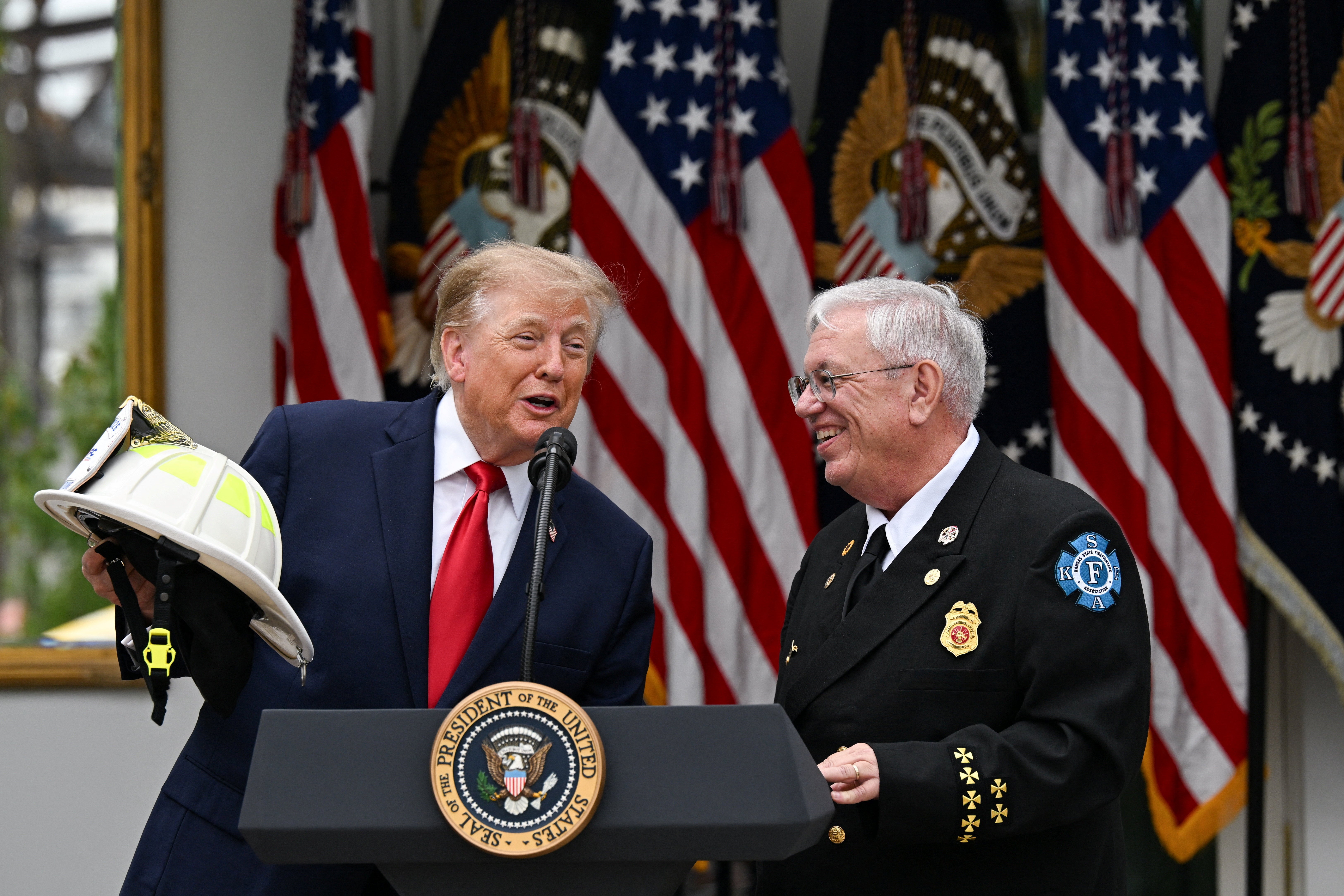 Chairman of the National Volunteer Fire Council Chief Steve Hirsch presents a fire helmet to Trump at the Rose Garden lunch