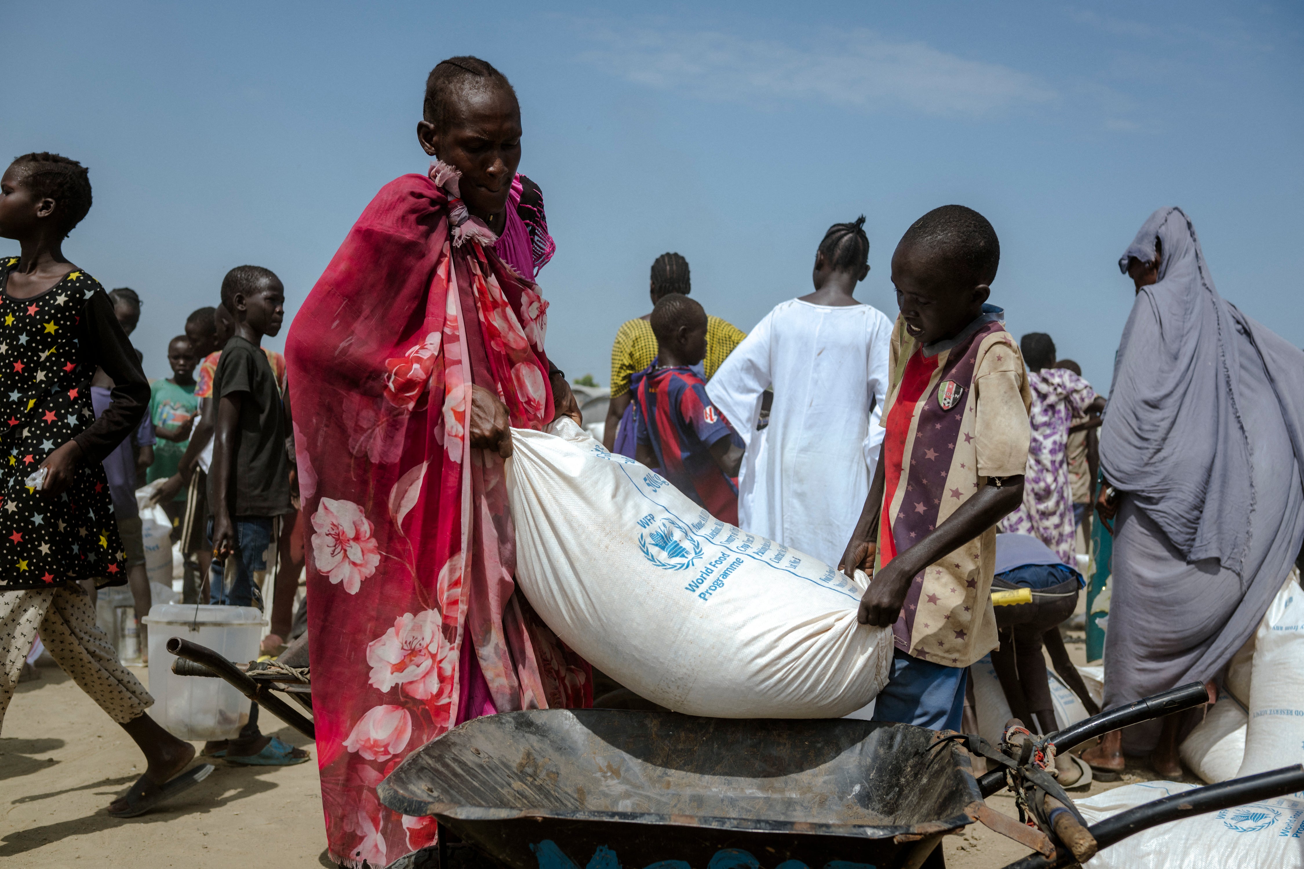 A young boy and his mother struggle to lift a heavy bag of maize into their wheelbarrow at a distribution center in the Bentiu internally displaced persons camp, Unity State, South Sudan (AFP/Getty)