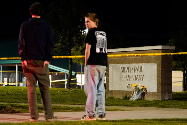 Flowers are placed at a school sign, as people gather following a shooting at Silver Rail Elementary School