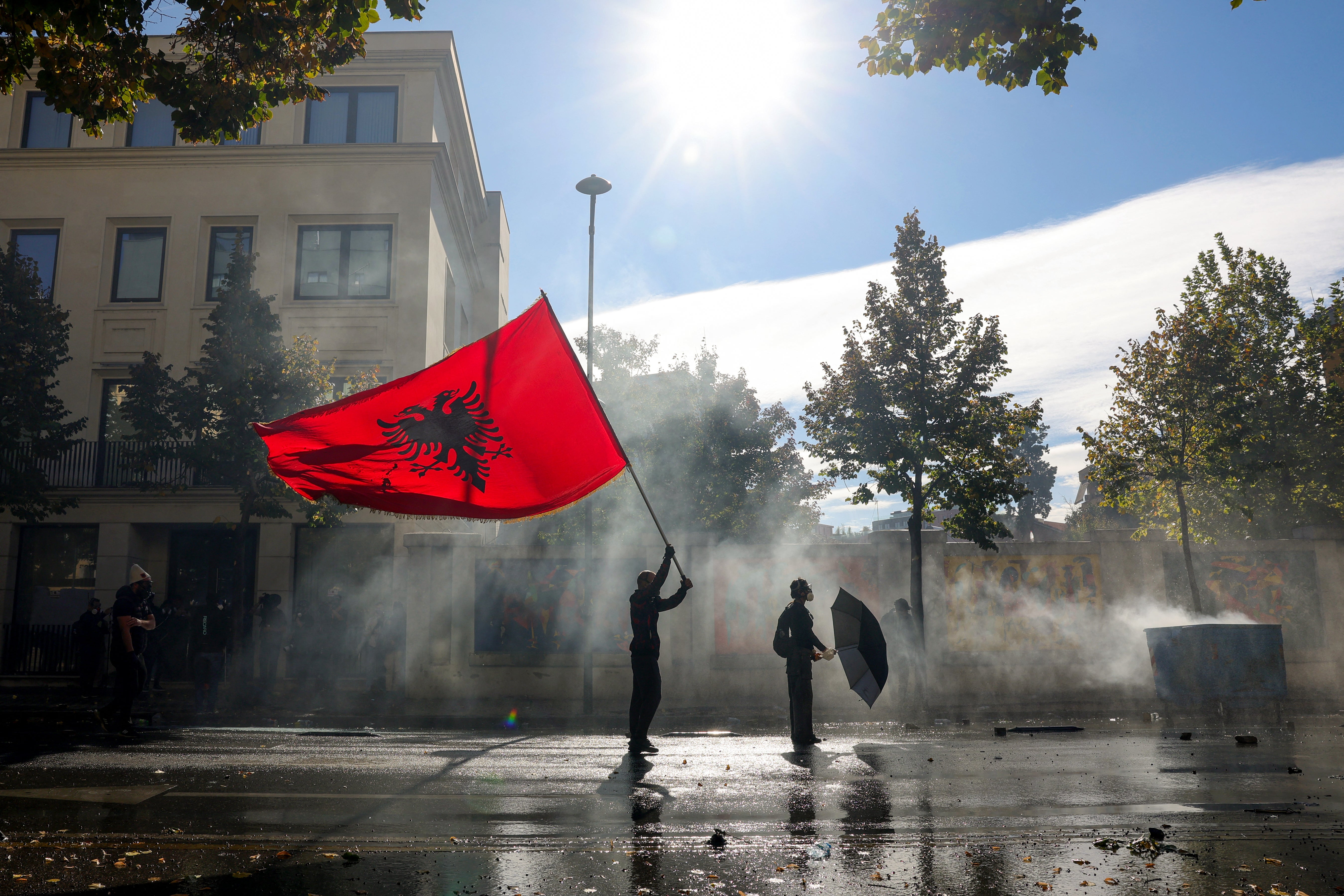 A protester holds an Albanian flag as he faces off with police water canon vehicles during an anti-government demonstration in central Tirana