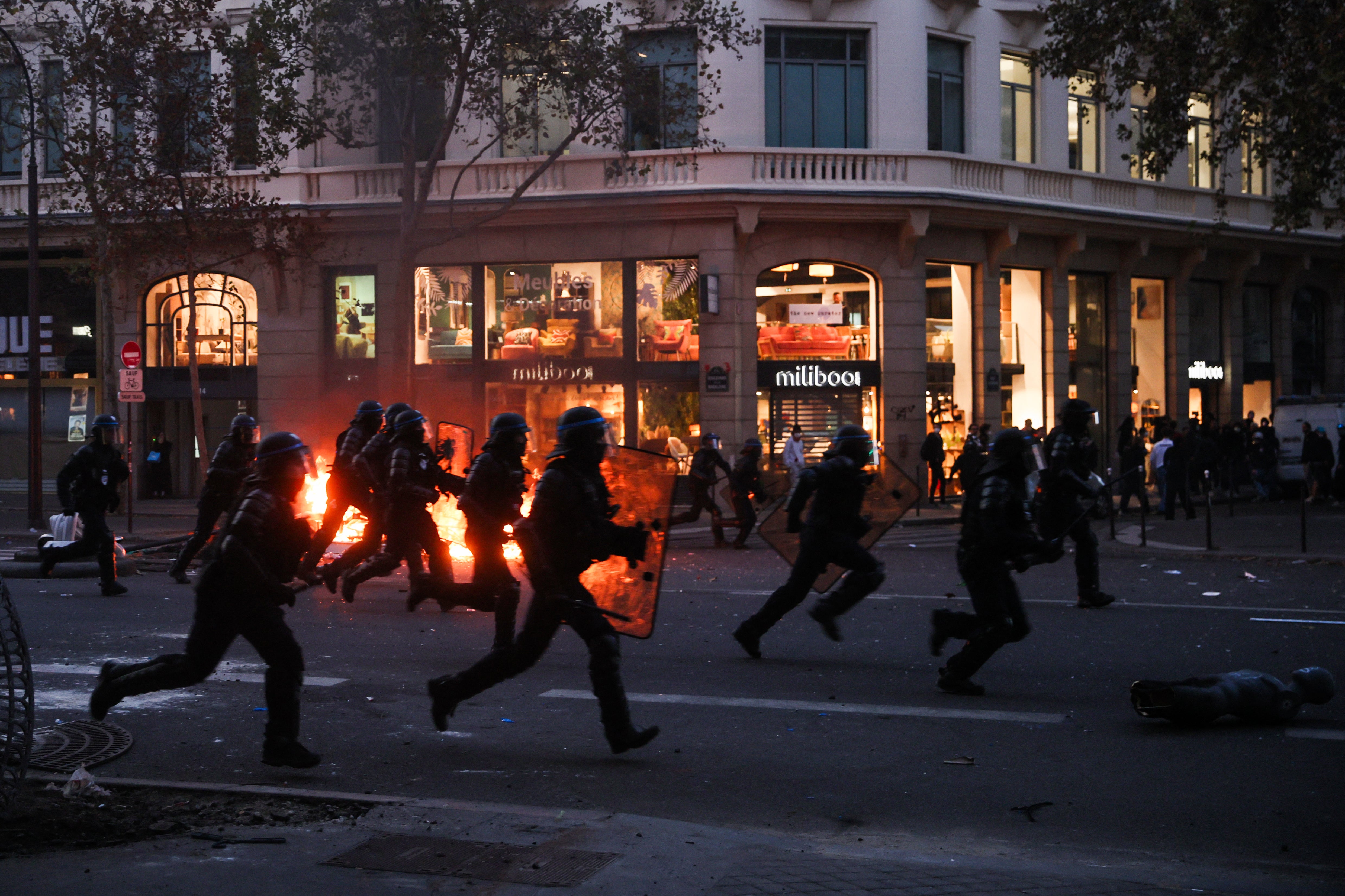 Police officers run past a fire at 
