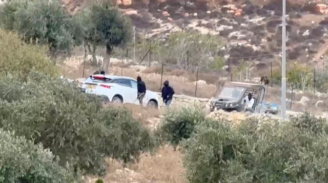 Vehicles at the site where Belgium's foreign minister says masked settlers in the Israeli-occupied West Bank attacked Palestinians, Catholic representatives and Western diplomats and officials