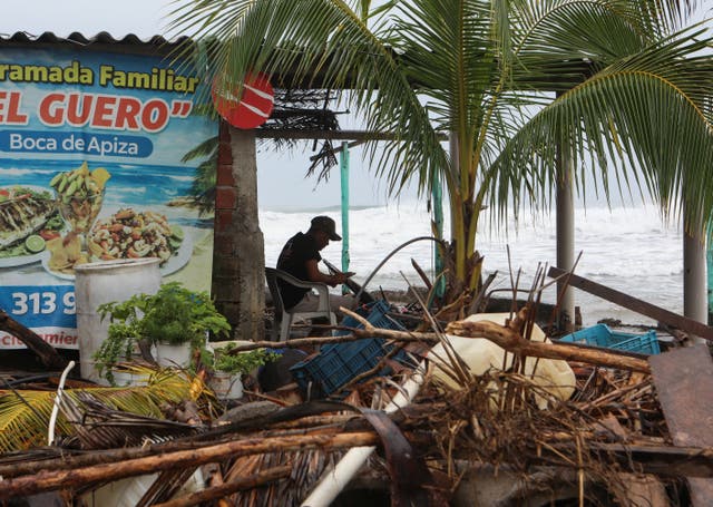 A man sits along the shoreline as Hurricane Trudy advances across the Pacific Ocean off Mexico's western coast, in Boca de Apiza, Michoacan state, Mexico