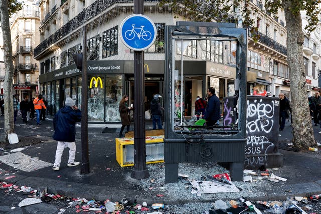 People walk past the damaged window of a McDonald's in Paris