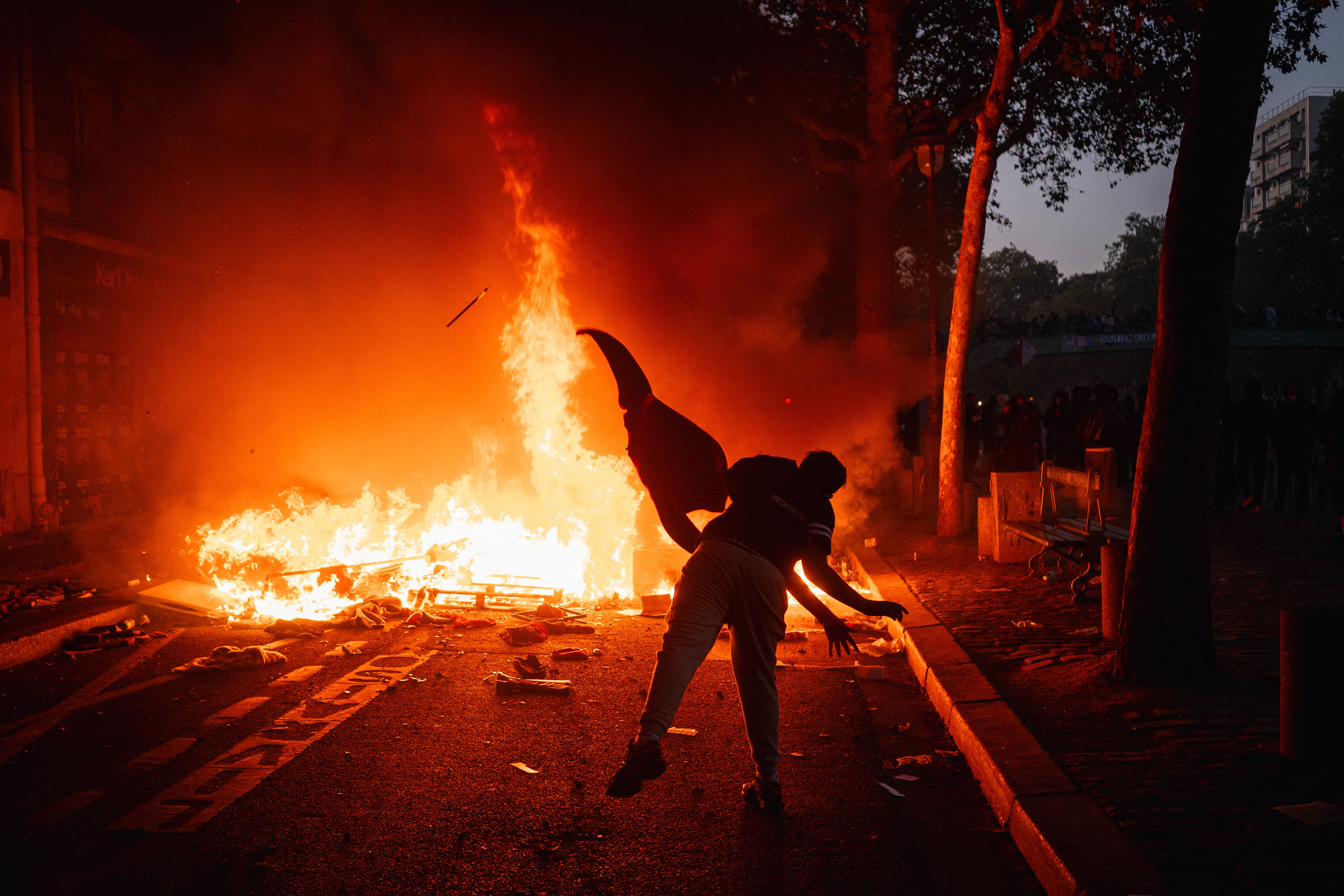 A protester feeds a fire with a material along the Canal Saint-Martin during ongoing protest action against the "high cost of living", in Paris on October 17