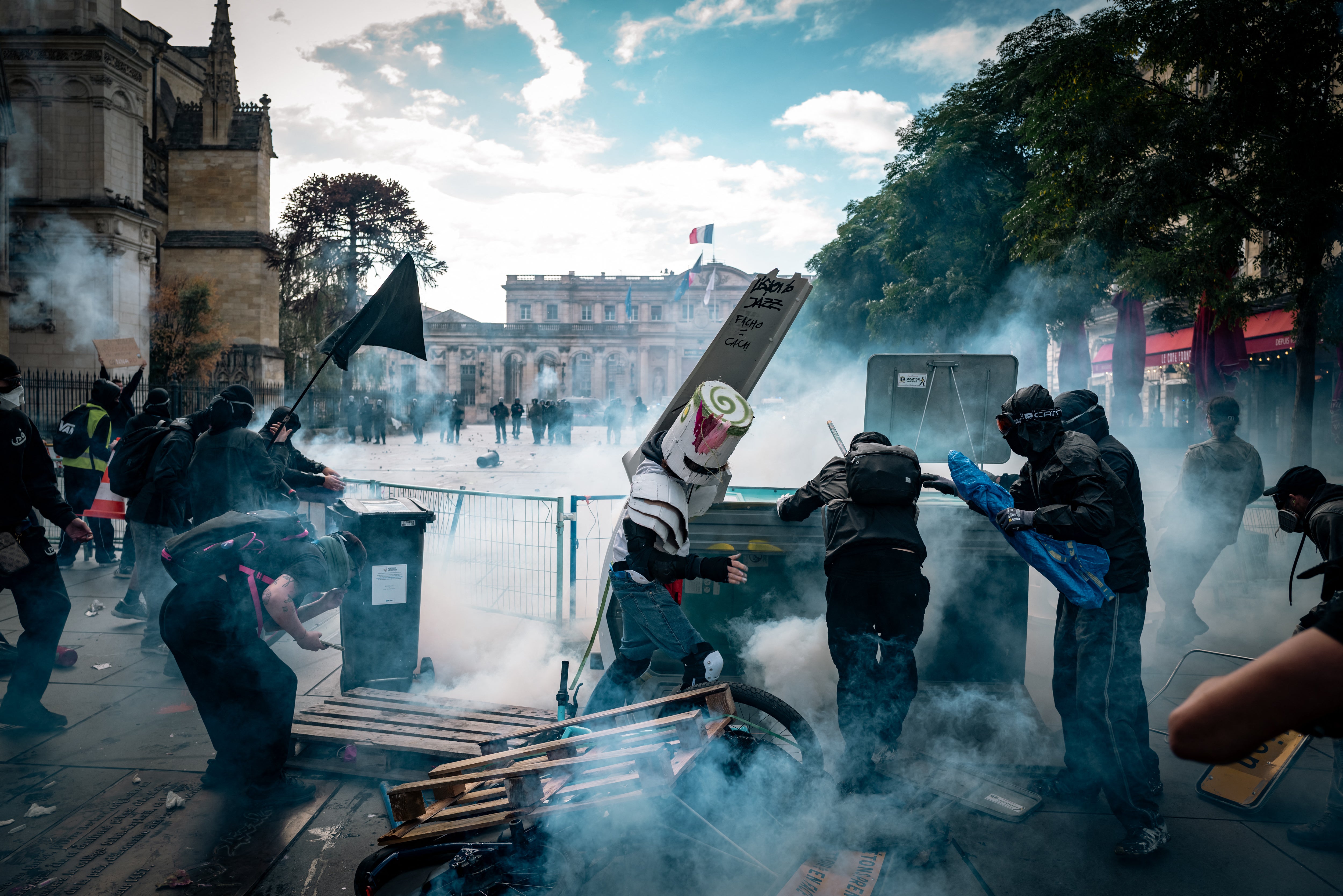 Masked demonstrators move around overturned debris amid thick smoke on Place Pey Berland, in front of Bordeaux City Hall, on Saturday