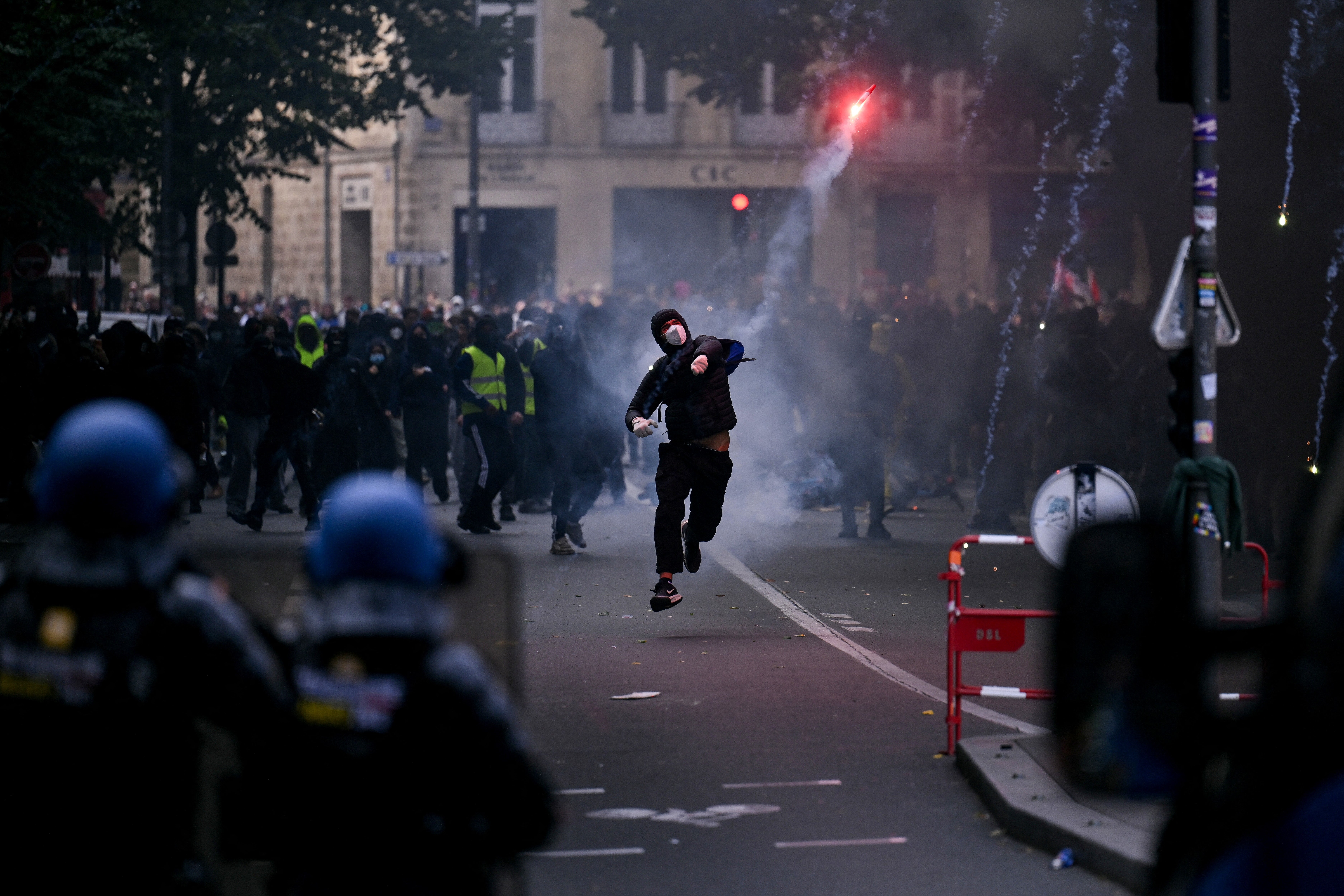 A protester throws a smoke flare towards French gendarmes during a demonstration in Bordeaux on Saturday