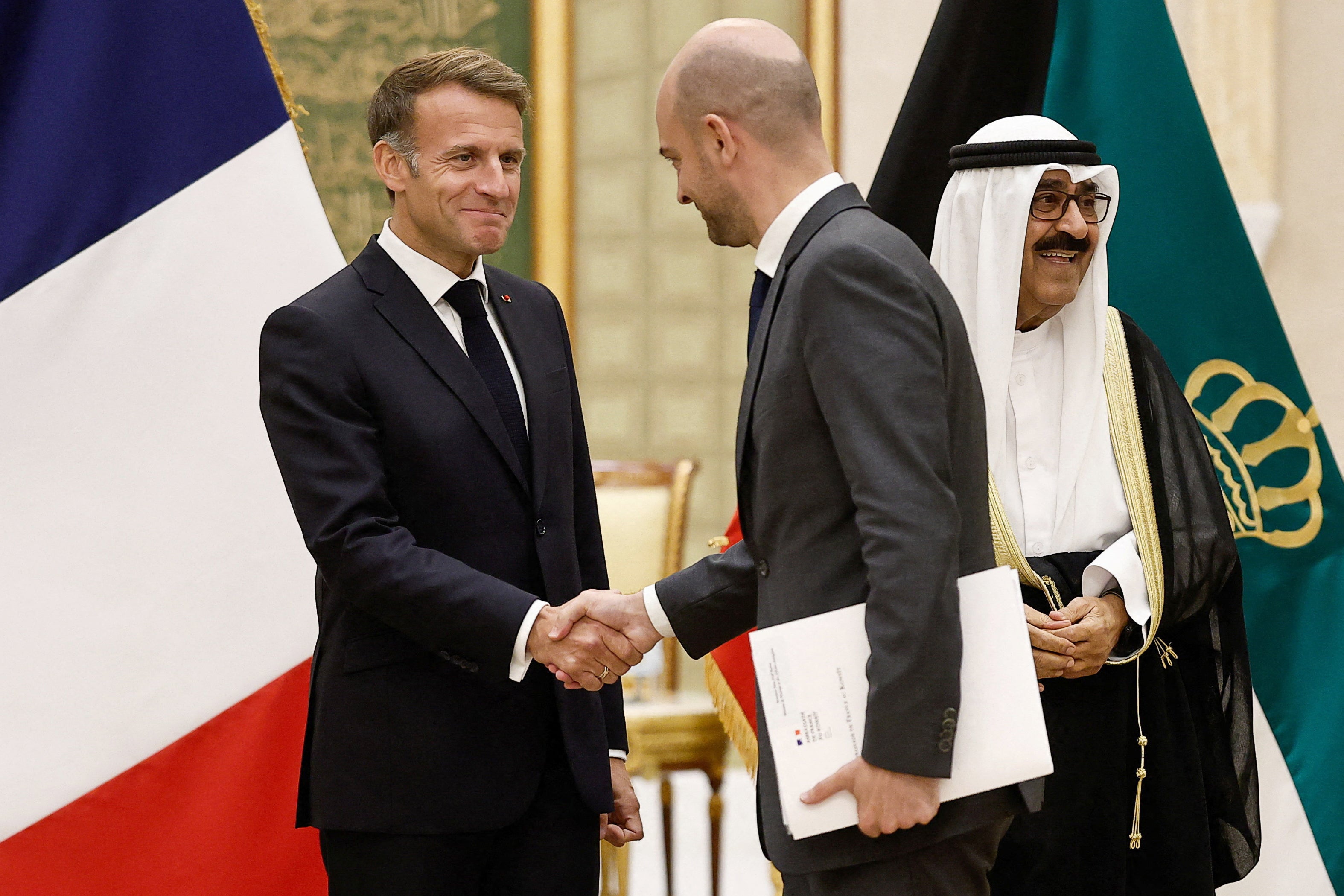 Emmanuel Macron (L) shakes hands with French foreign minister Jean-Noel Barrott at Bayan Palace in Kuwait City on October 19