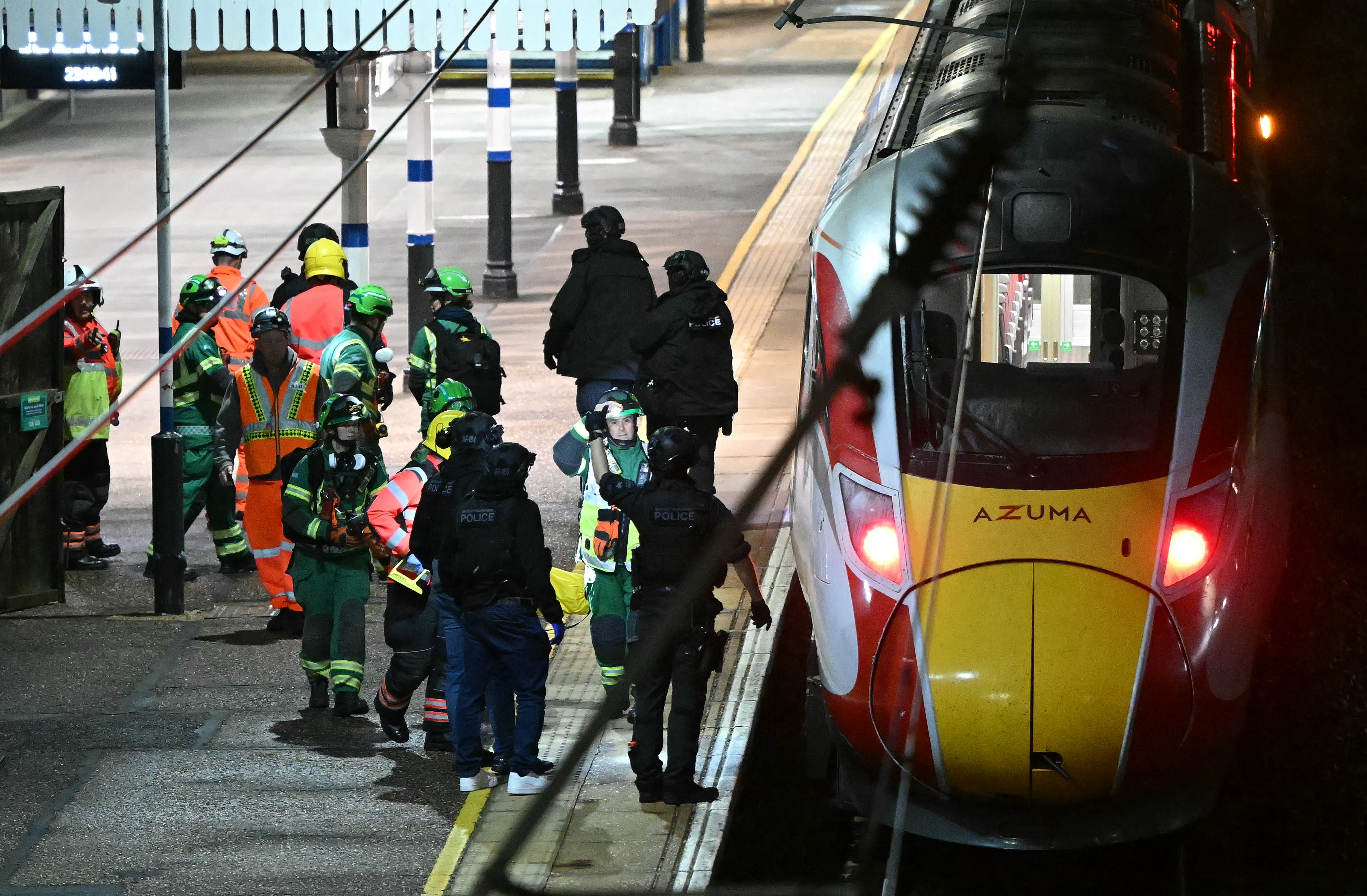 Police officers and members of the Emergency services work alongside an LNER Azuma train at Huntingdon Station in Huntingdon