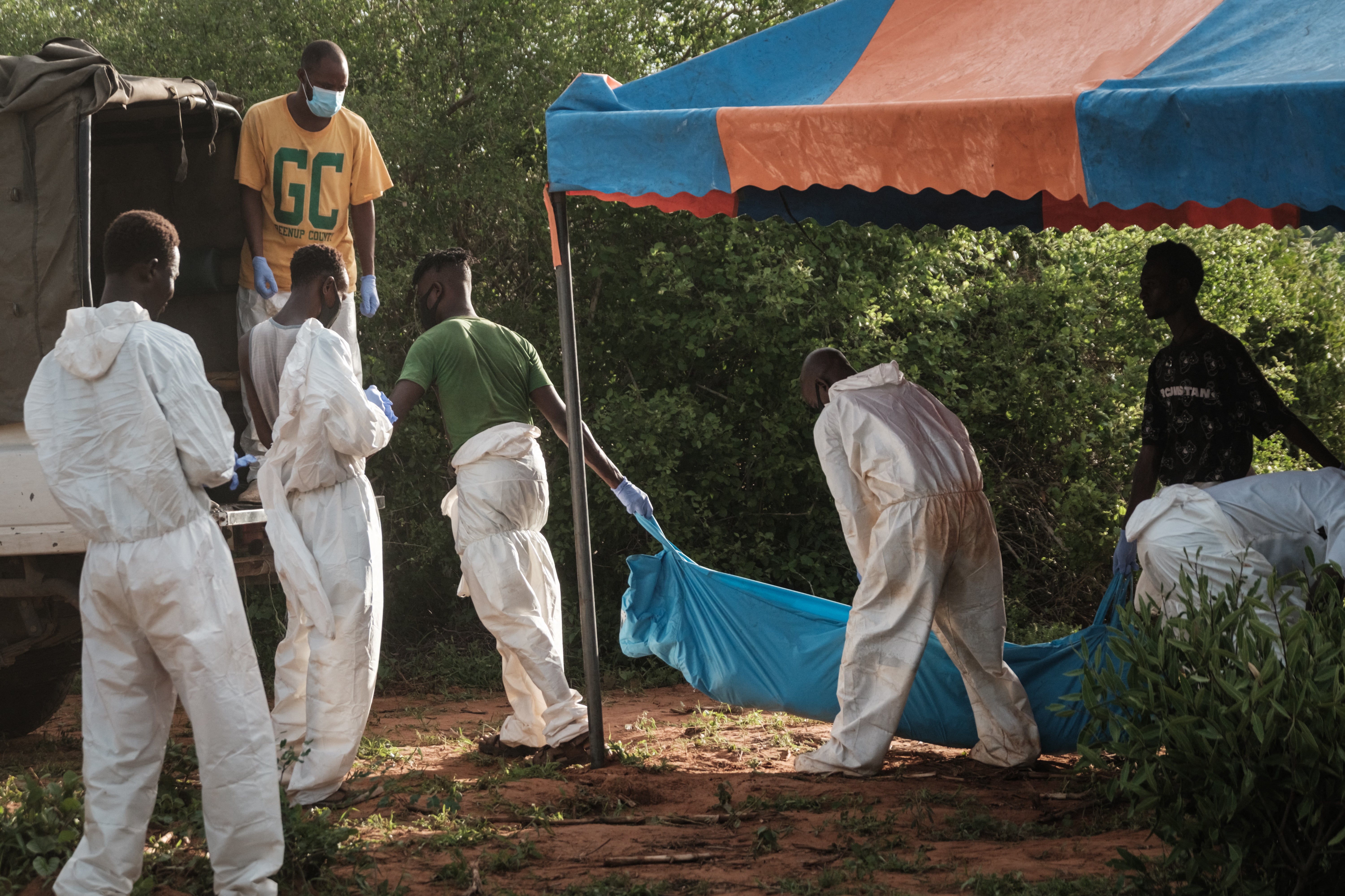 Workers carry the exhumed bodies in bodybags to the mortuary, at the mass-grave site in Shakahola, outside the coastal town of Malindi, on 25 April, 2023.