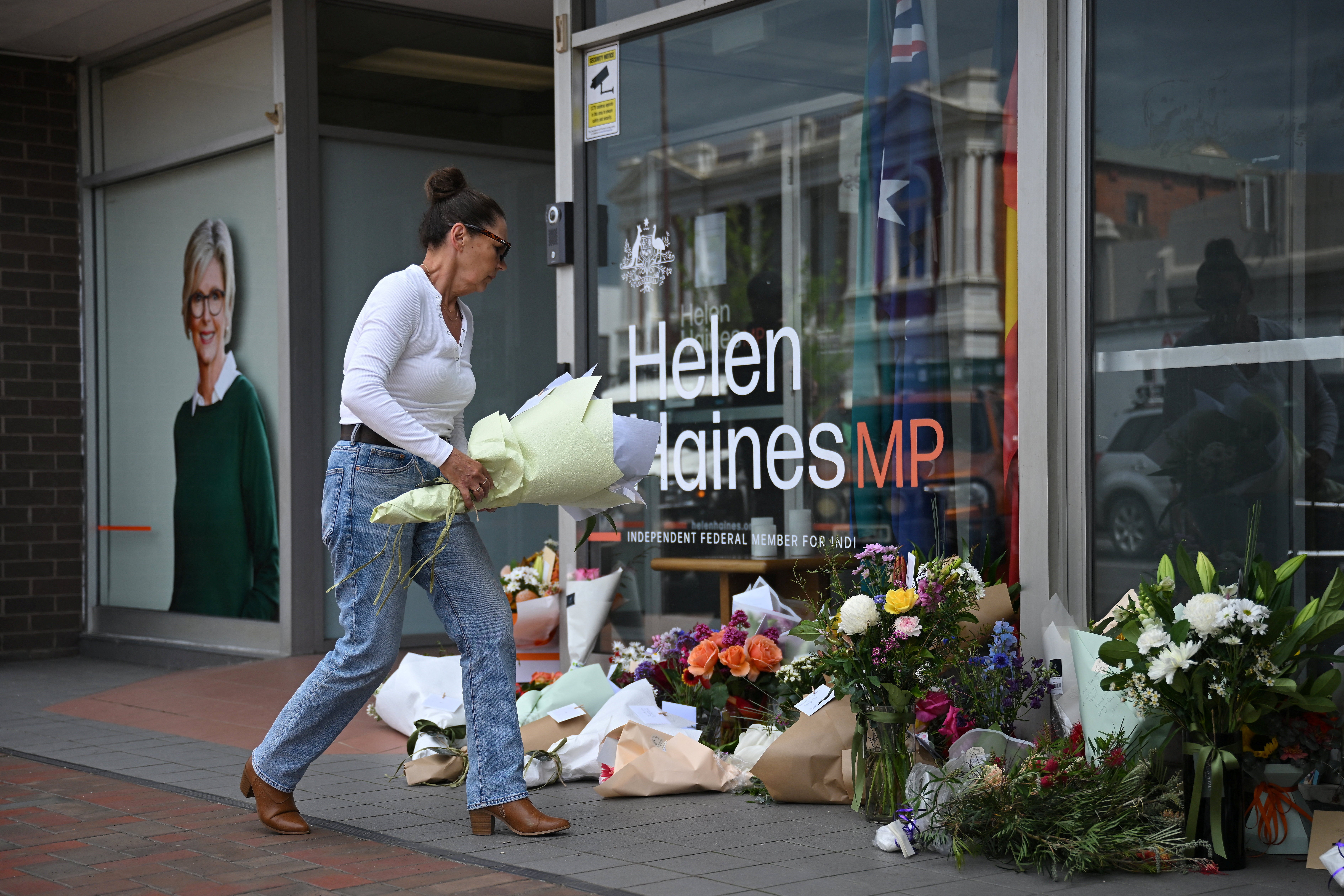 A woman leaves flowers outside the electoral office of independent Australian lawmaker Helen Haines, who was deliberately struck by a car outside her office on Monday
