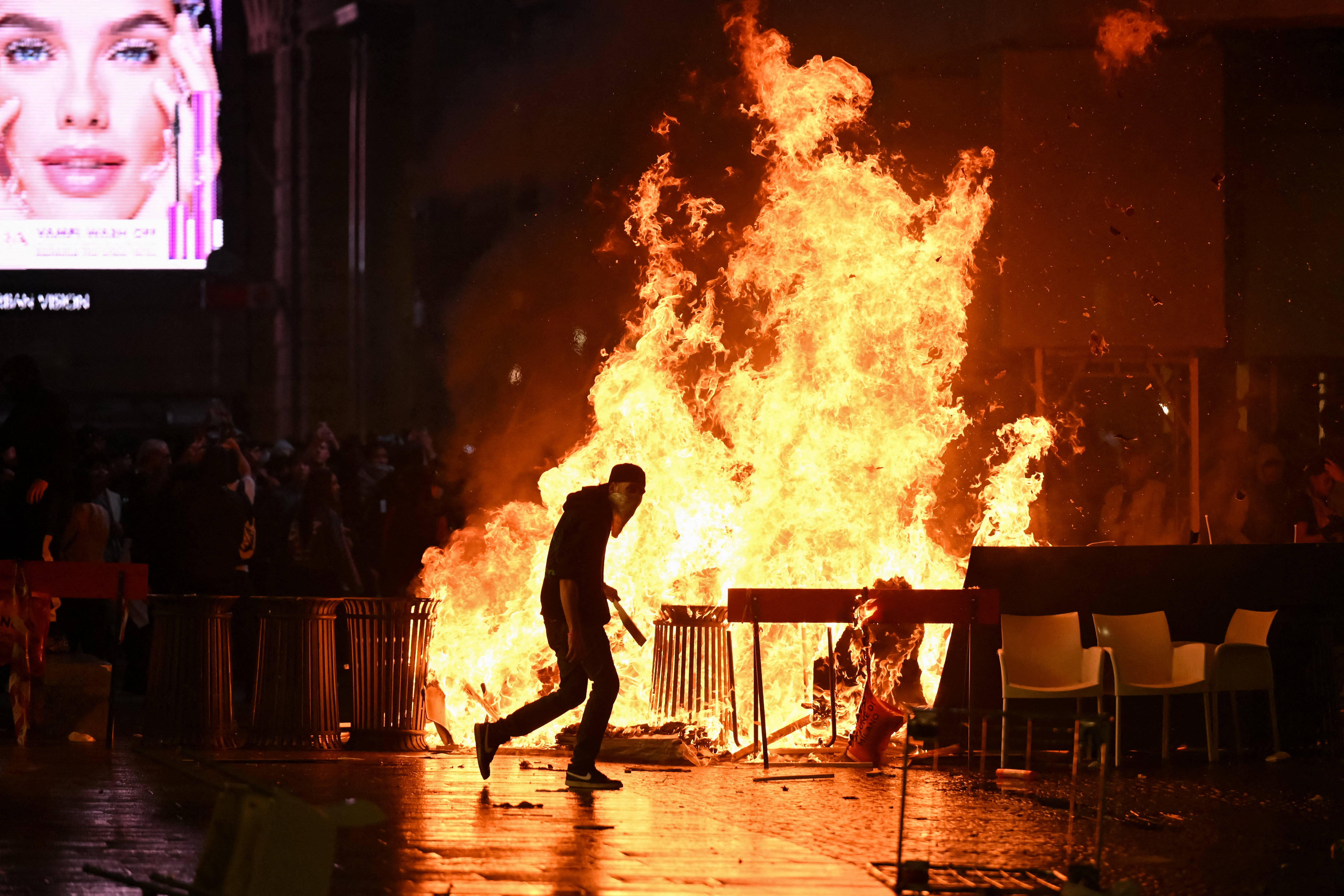 A barricade of cardboards and trash is set on fire as demonstrators clash with Police during an anti-government protest organized by the Italia in Piazza movement, at Piazza Duomo in Milan
