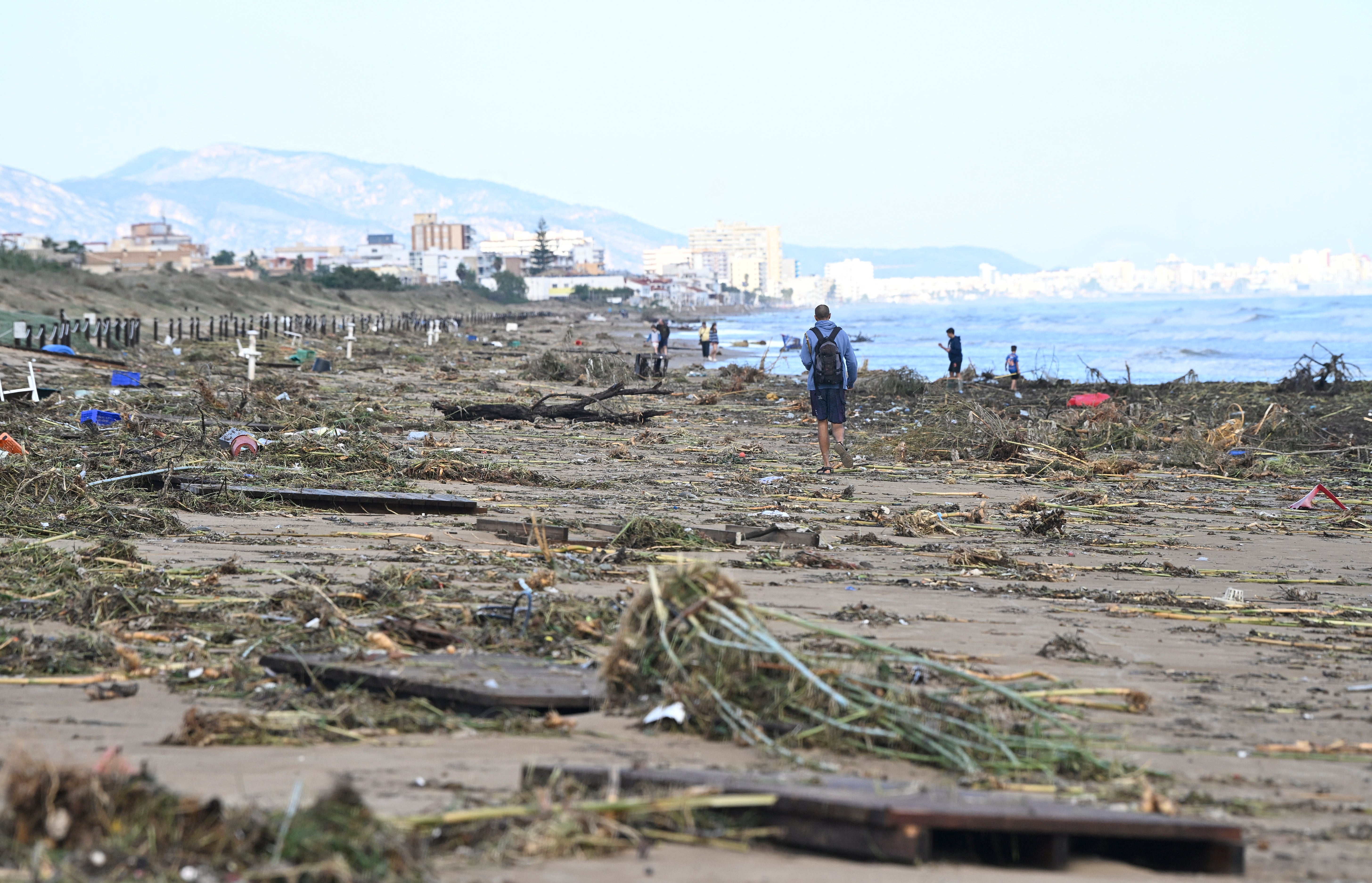 A man walks on the beach littered with debris following torrential downpours in Oliva, in the Valencia region, eastern Spain on 20 October