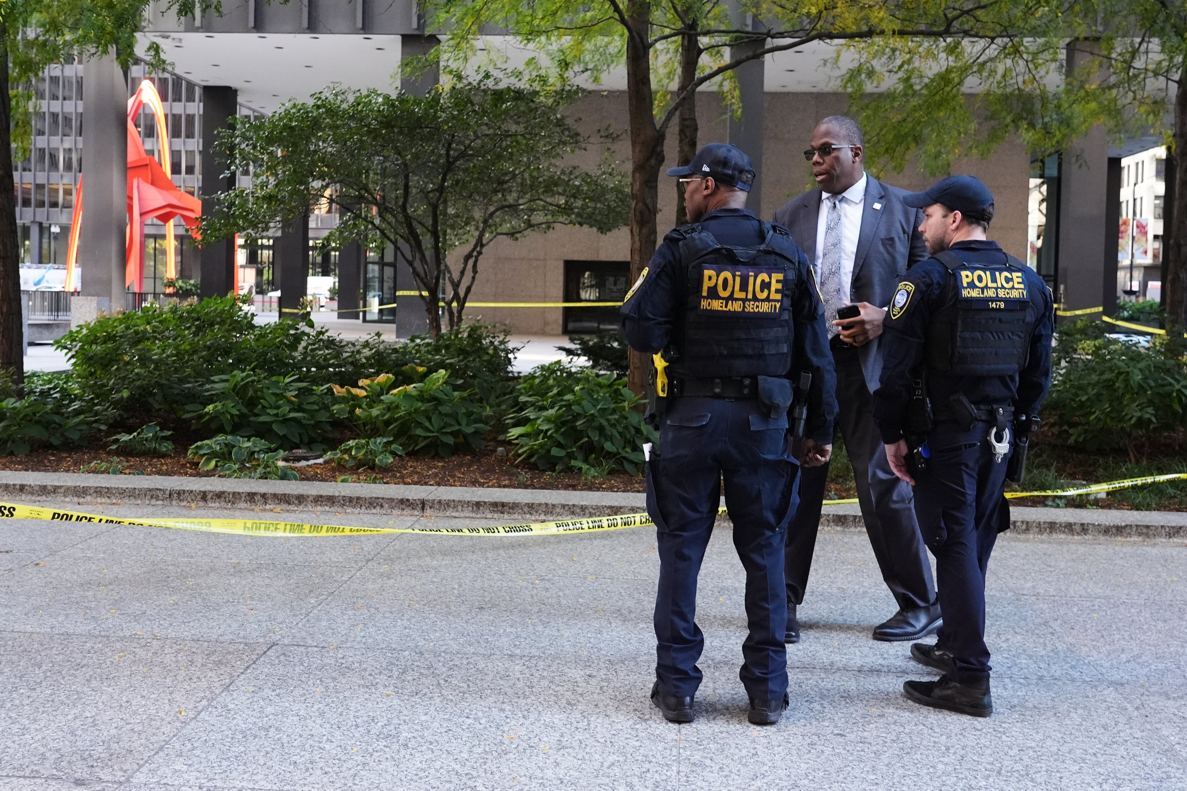 Department of Homeland Security officers and a law enforcement officer respond to the scene of a shooting near the Kluczynski Federal Building