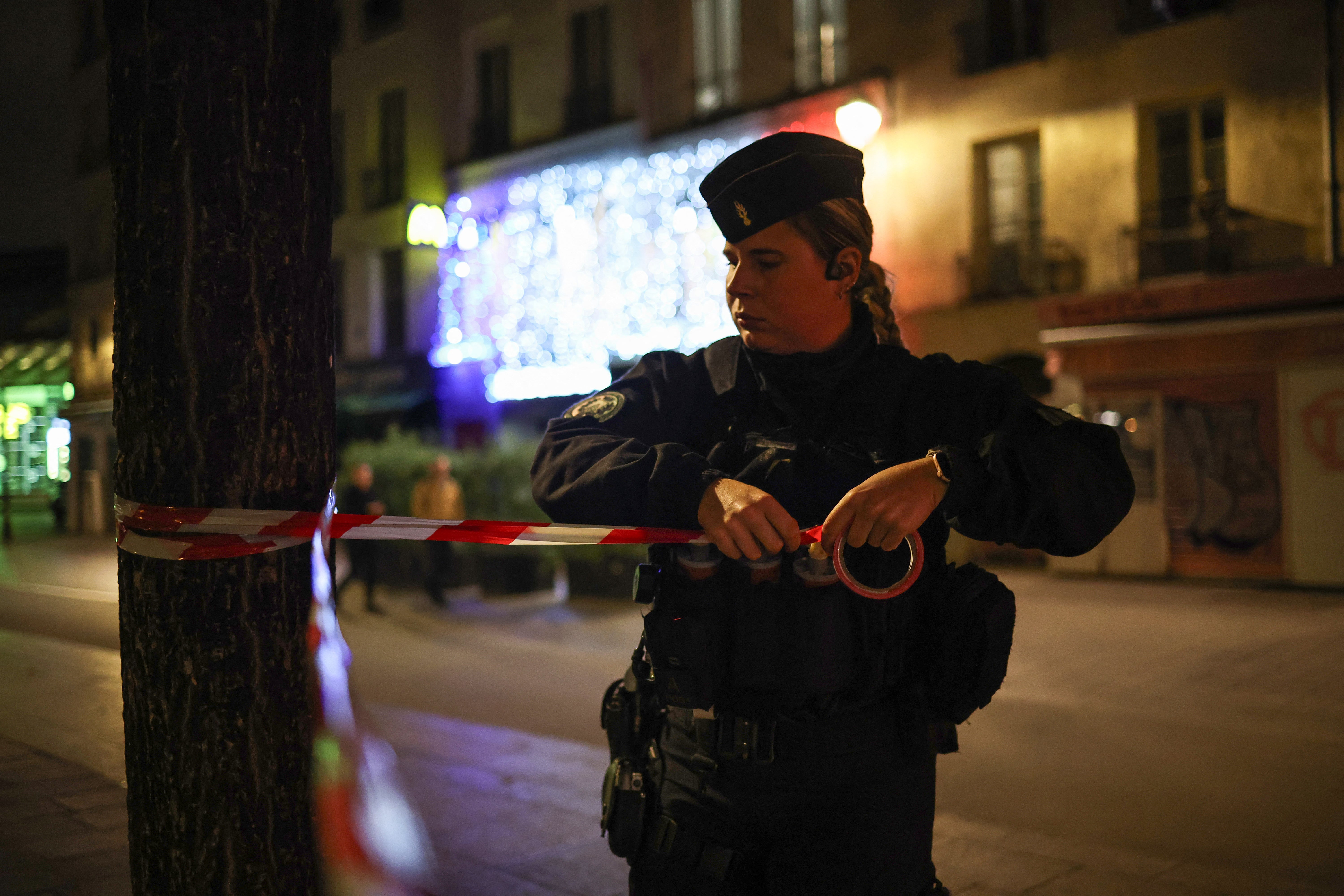 A police officer puts in place a perimeter tape near Chatelet - Les Halles to enforce a curfew, in Paris on 20 October