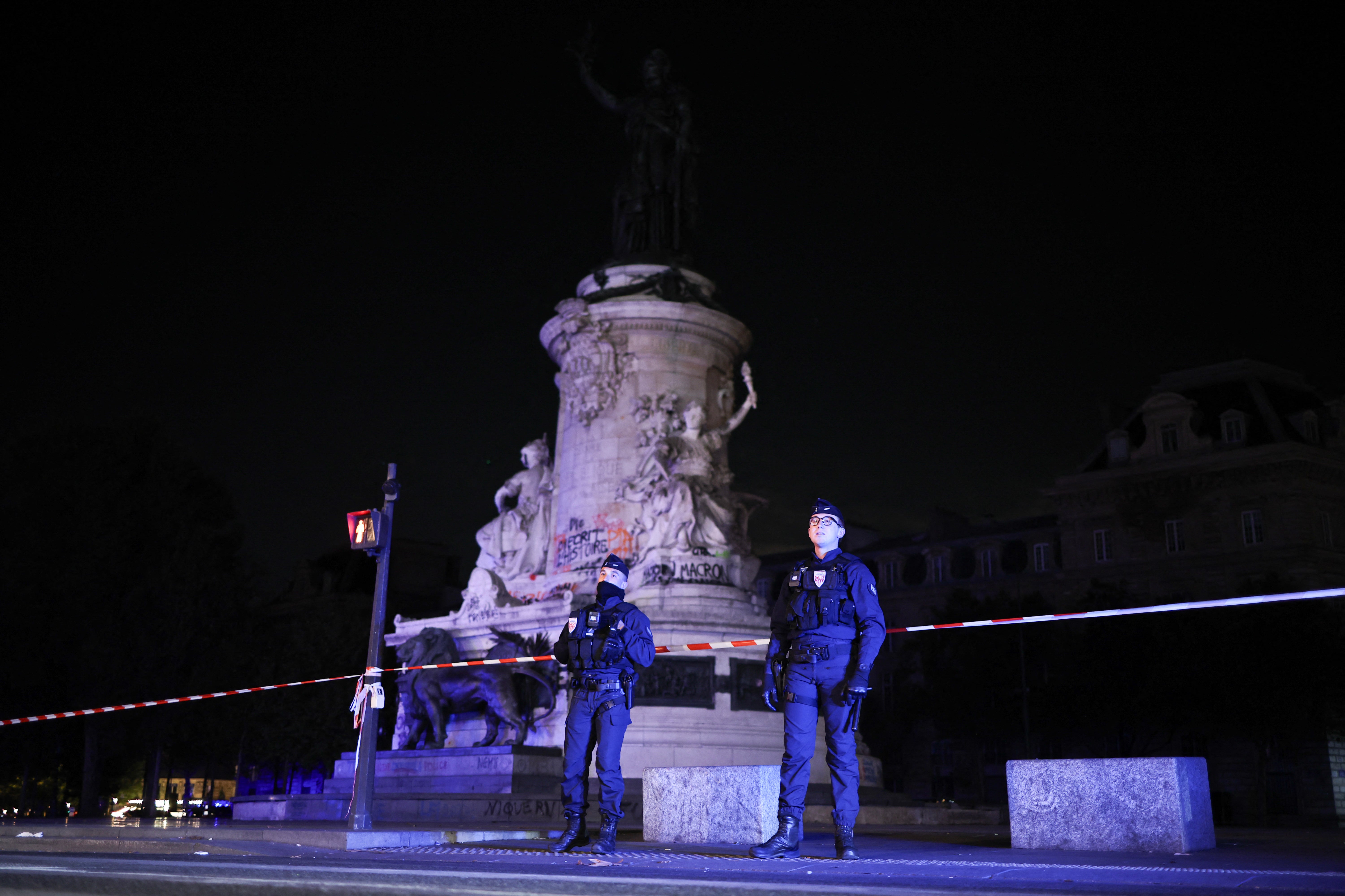 Police officers stand guard at Place de la Republique during a partial curfew in Paris in the early hours of 21 October