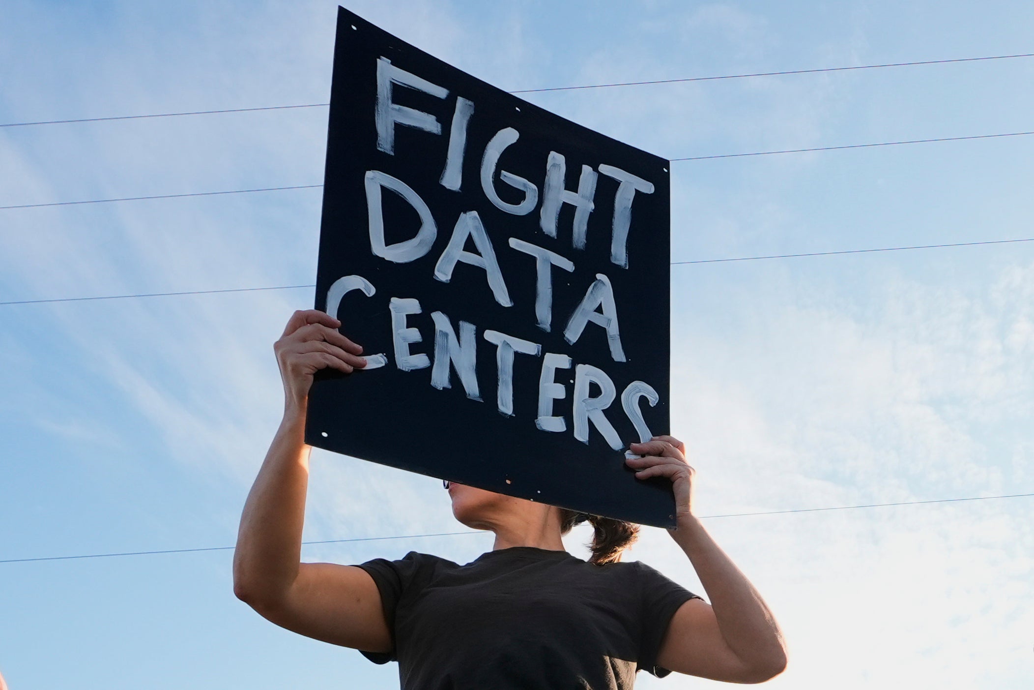 A protester holds a Fight Data Centers signs Monday, Oct. 12, 2026, in Mason, Michigan