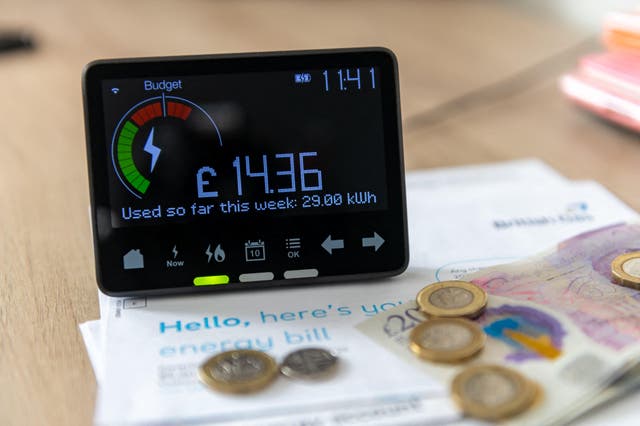 A smart energy meter showing latest reading surrounded by household energy bills and coins (Alamy/PA)