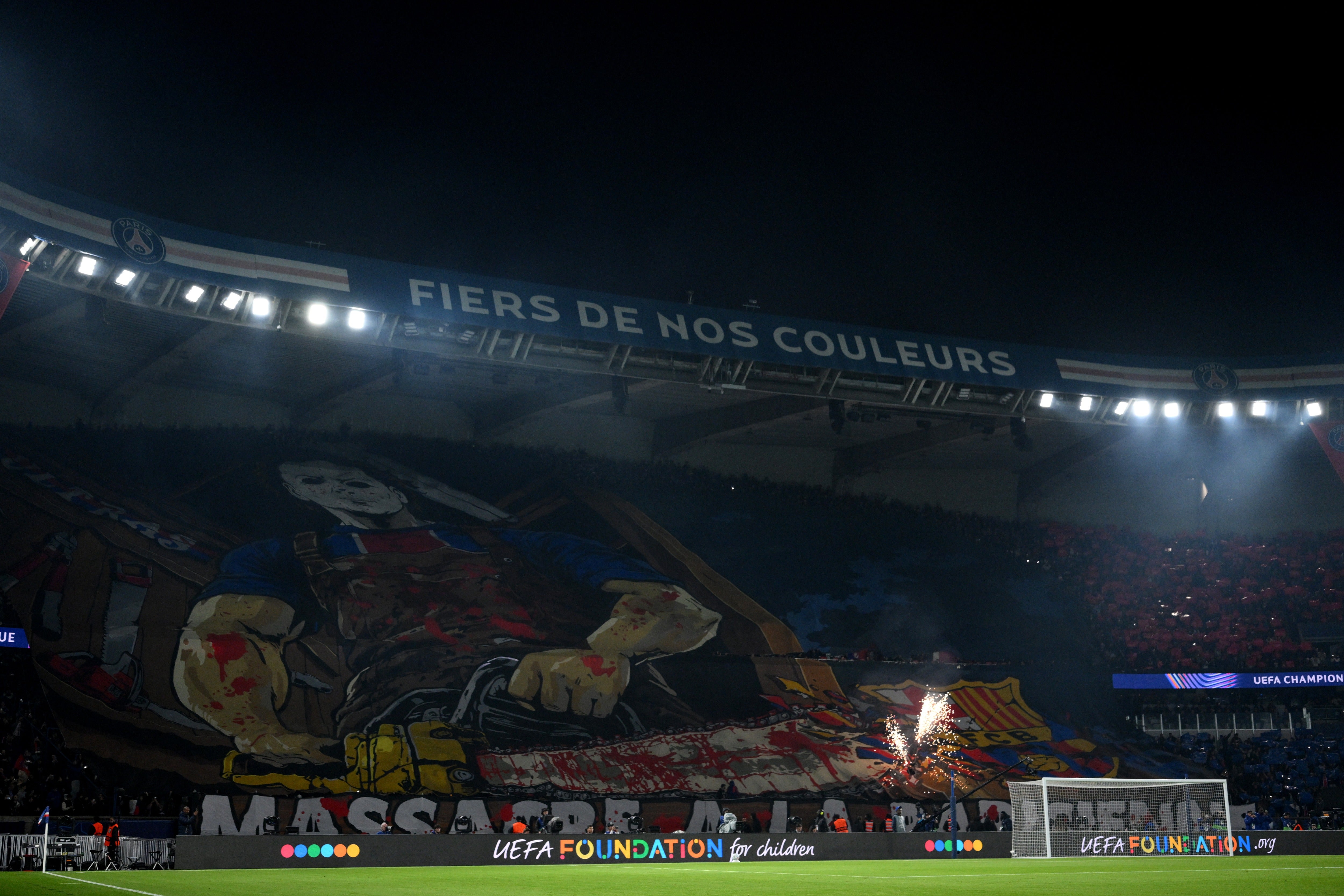 Tifo displayed by PSG fans showing a masked man holding a bloody chainsaw over the FC Barcelona crest at the Parc des Princes.