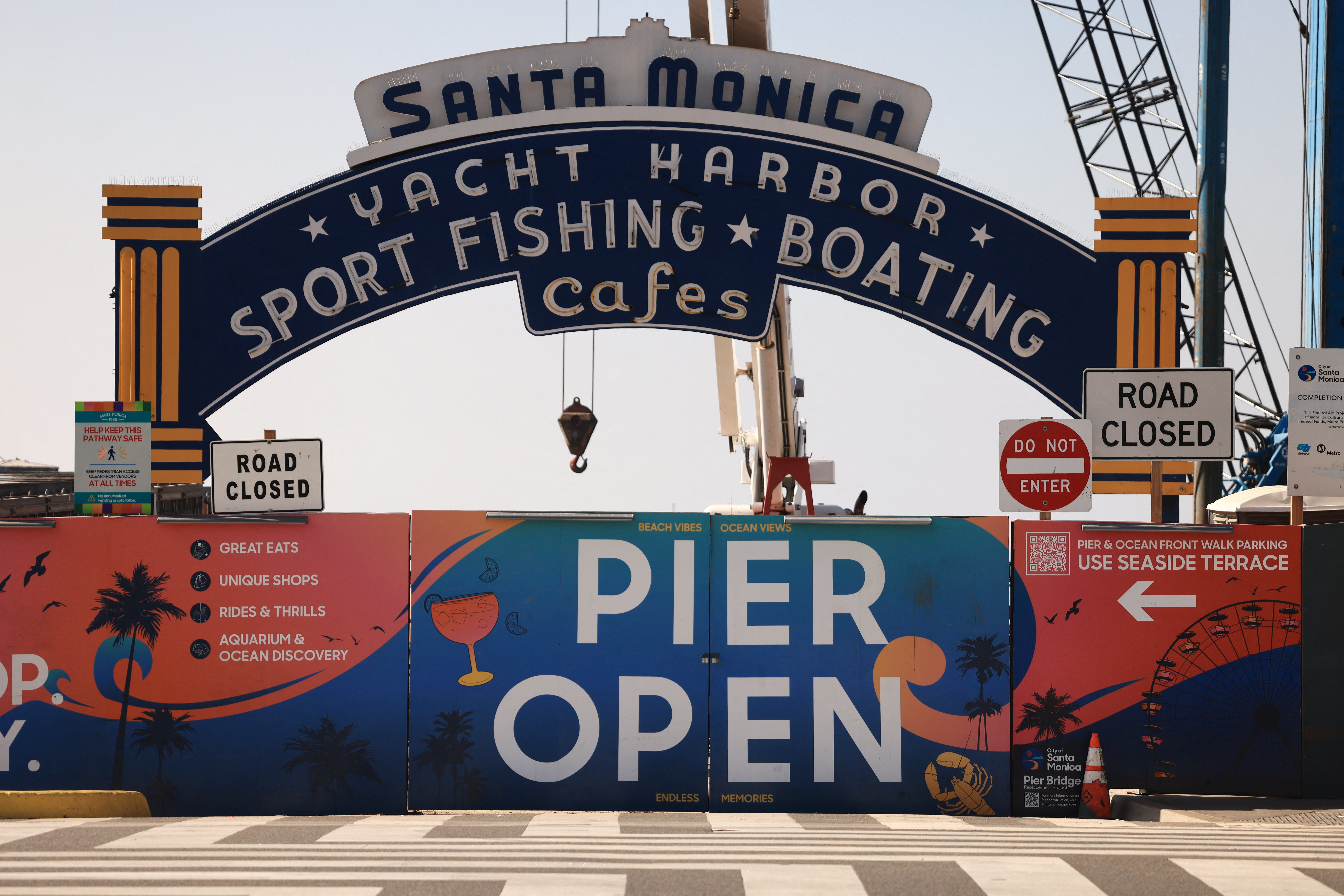 Entrance to the Santa Monica Pier is partially blocked off as workers remove the sign