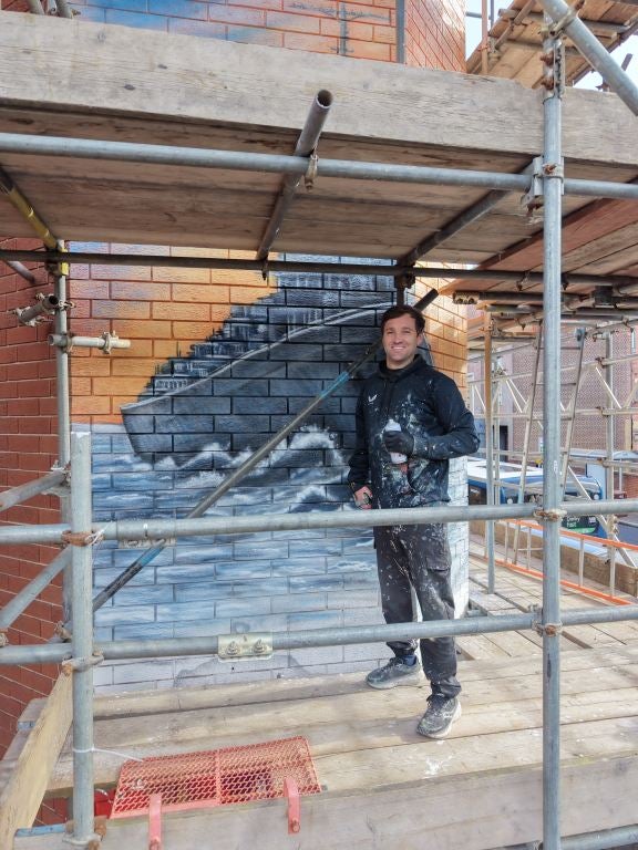 Neil Keating, at work on a mural on the side of Ilkeston Town Hall i