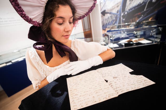 A lady in period costume looks at a letter written by Emma Hamilton sent to Lord Nelson which arrived after his death