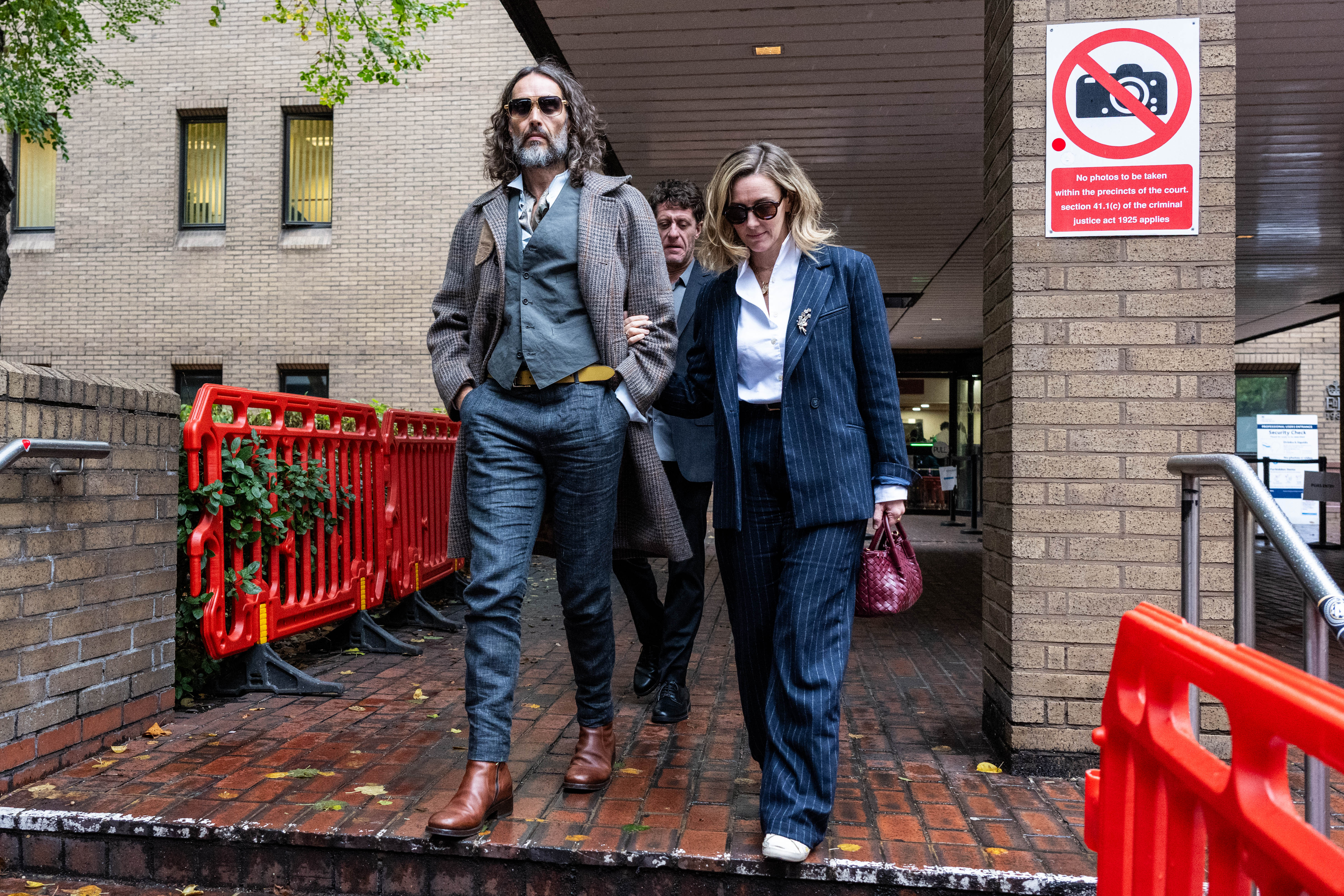 Russell Brand departs court with his wife Laura Gallacher (R) during his trial, where he faces rape and sexual assault charges at Southwark Crown Court on October 21, 2026 in London