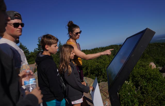 Visitors read a sign at the summit of Cadillac Mountain in Acadia National Park in Maine, on Saturday, July 11, 2026. (AP Photo/Jessie Wardarski)
