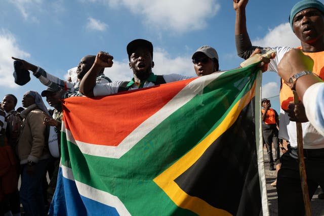 Demonstrators hold a South African flag as they chant slogans during a protest against undocumented migrants organised by the March and March and Operation Dudula groups in Cape Town on May 23, 2026