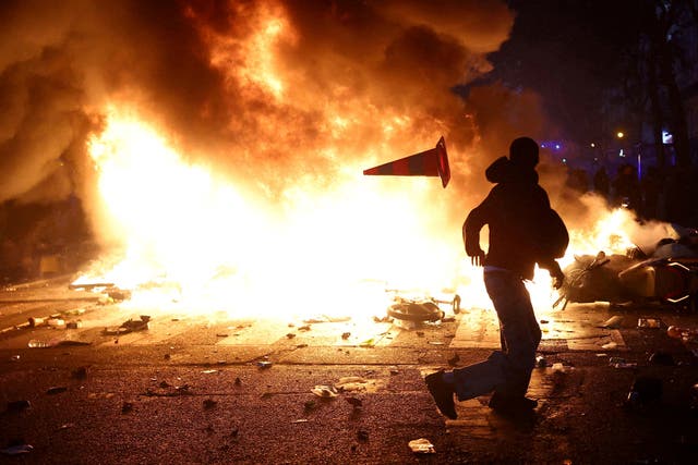 A man throws a plastic traffic cone through a burning barricade amid clashes during a day of demonstrations against the cost of living and rising fuel prices in Paris as part of nationwide protests called by the "Yellow Vests" movement, joined by French high school and university students, teachers and parents demanding better school conditions and government action, as well as labour unions, workers, farmers and retirees, France, October 17, 2026.