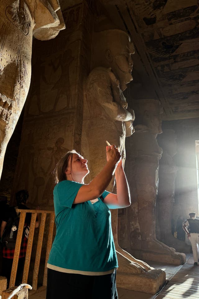 A tourist films the sun as it sends a beam of light into the Great Temple of Ramses II's dark inner chamber in Abu Simbel, 870 kilometers (540 miles) south of Cairo, Egypt, Thursday, Oct. 22, 2026, a rare 3,200-year-old astronomical ceremony that happens twice a year