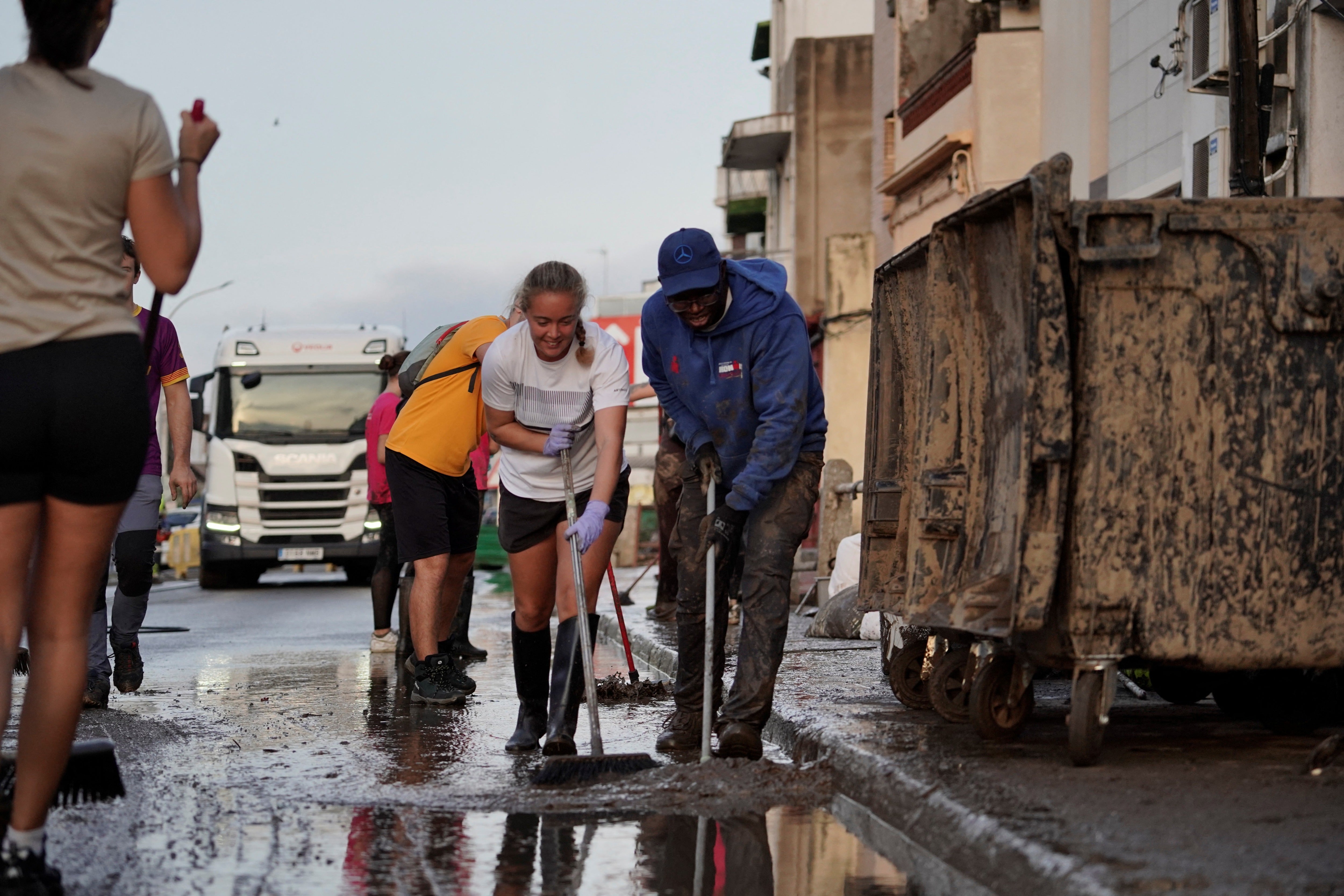 Volunteers sweep off muddy water from the street following torrential rains in Pineda de Mar, north of Barcelona, Spain