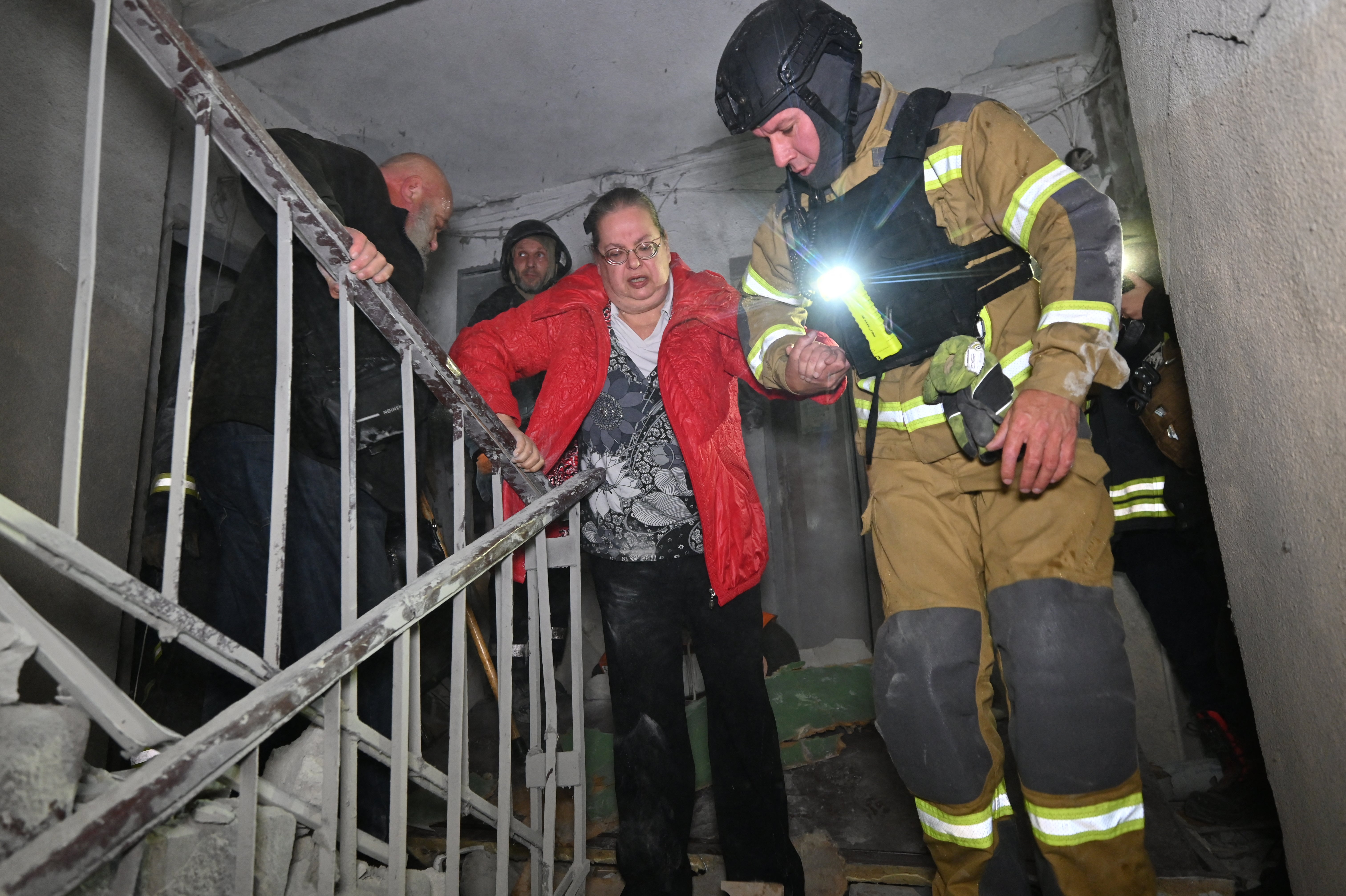 Спасатели помогают раненой женщине выбраться из жилого дома, поврежденного в результате российской воздушной атаки на Харьков 28 сентября.