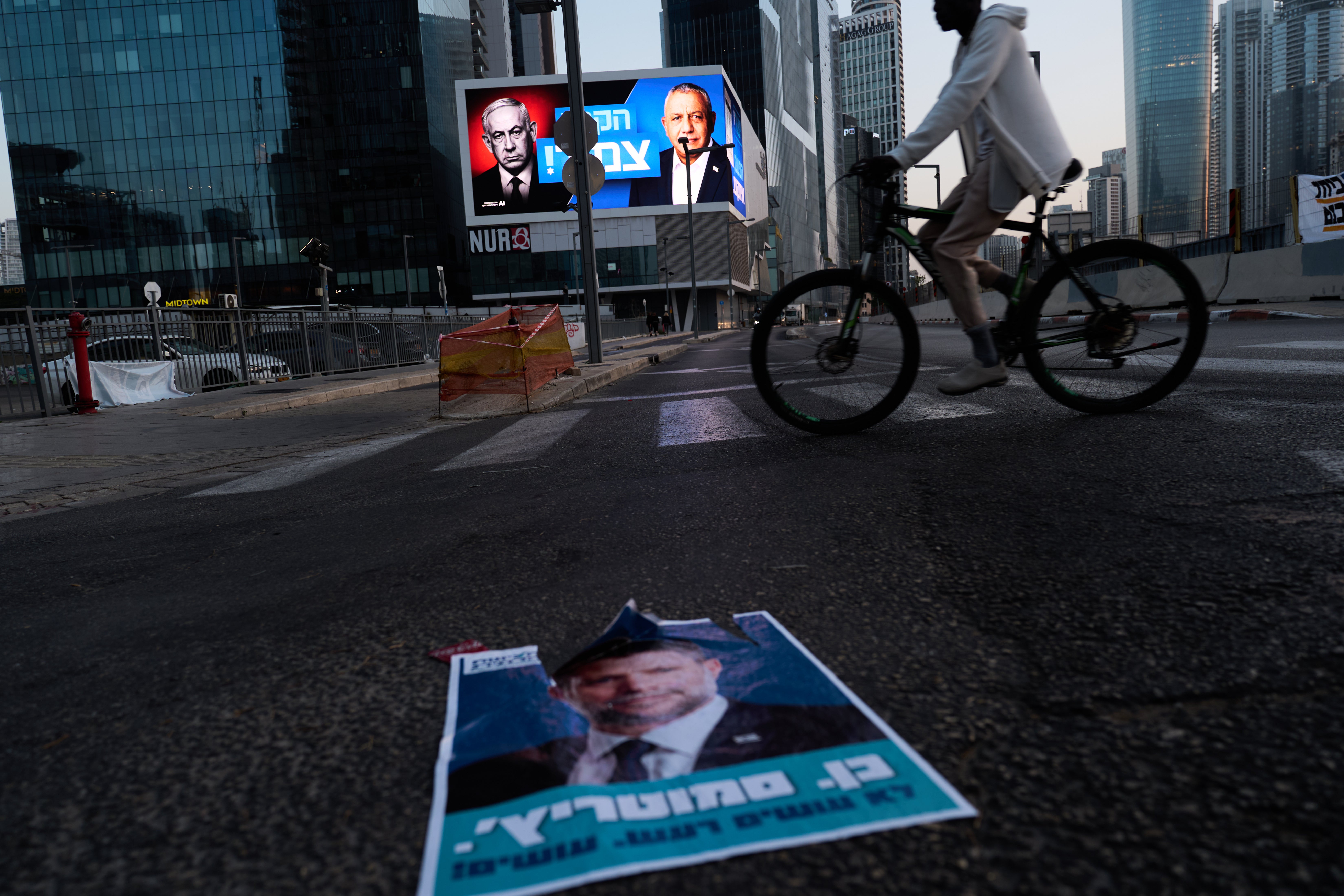 A cyclist passes a campaign billboard featuring Netanyahu, left, and his main rival, opposition candidate Eisenkot, with a message in Hebrew that reads 