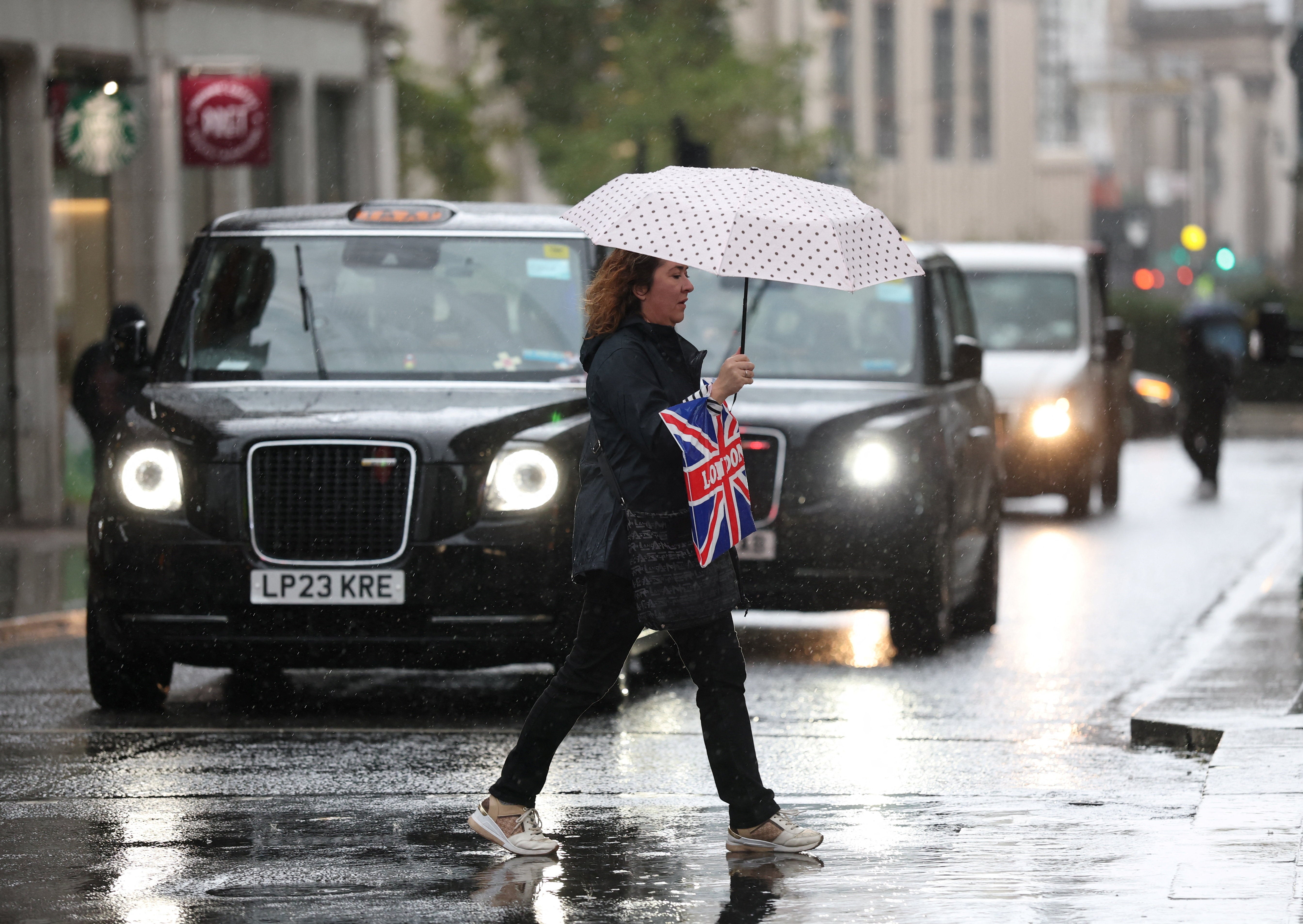A person shelters from the rain under an umbrella in Oxford Street during Storm Austen in London, Britain, October 23, 2026. REUTERS/Isabel Infantes