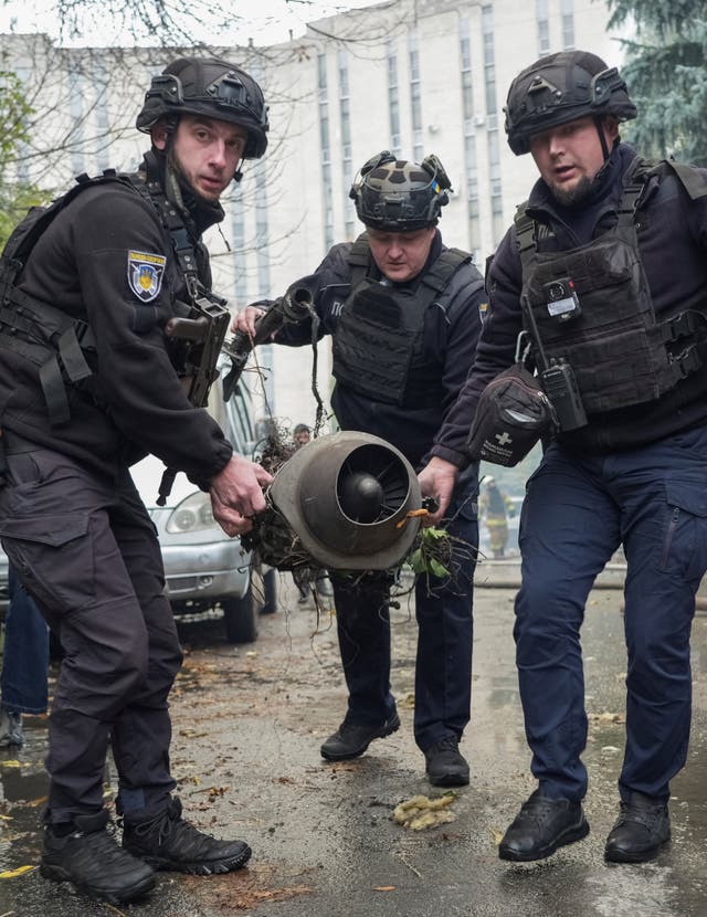 Police officers carry a part of a Russian drone which hit an office building damaged during a Russian jet drone strike in Kharkiv, October 23, 2026