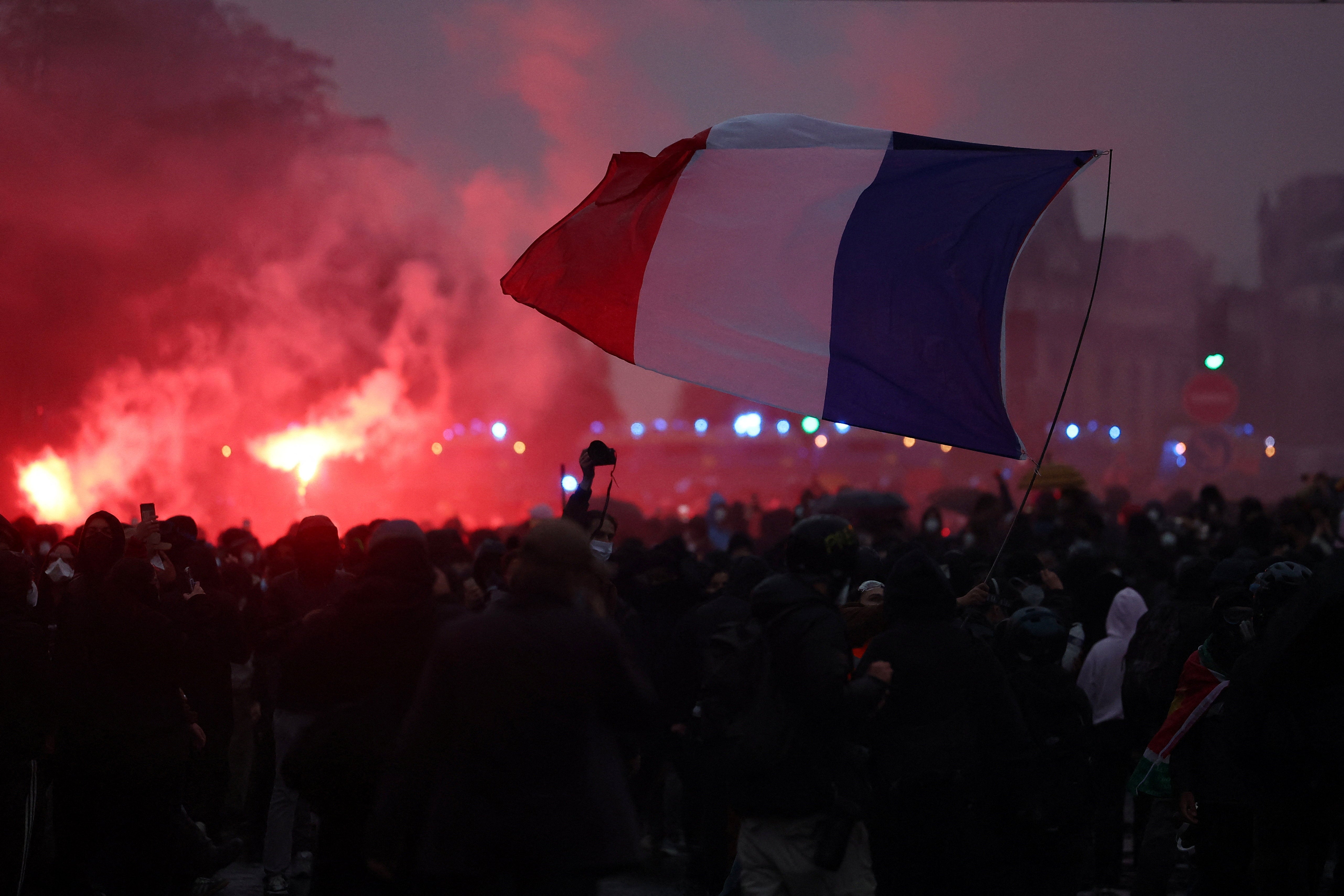 Protesters hold a French flag amid clashes during demonstration organised by labour unions in Paris