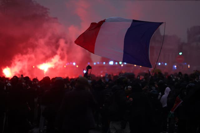 Protesters hold a French flag amid clashes during demonstration organised by labour unions in Paris