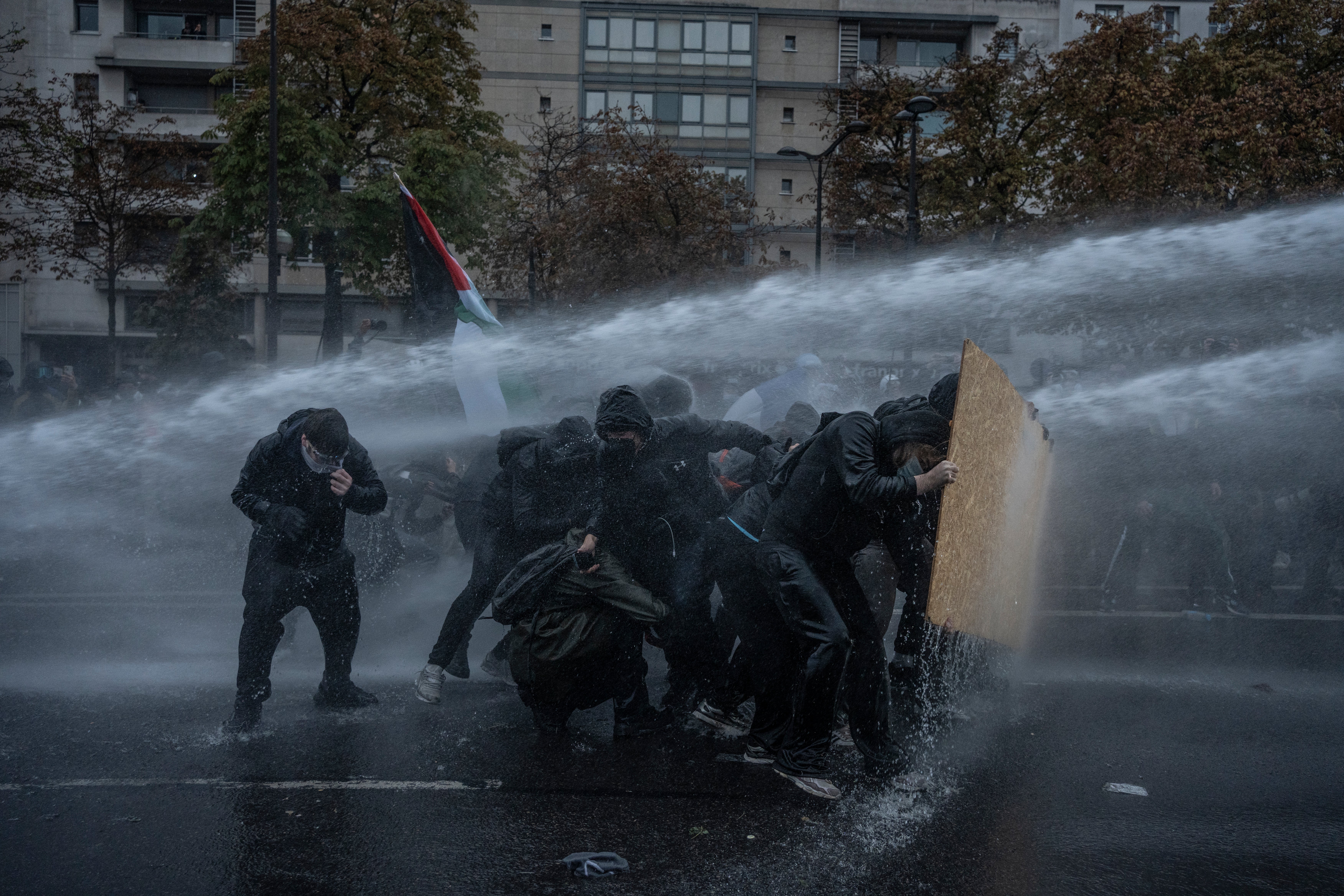 Protesters shield themselves from a water cannon on the streets of Paris on October 24