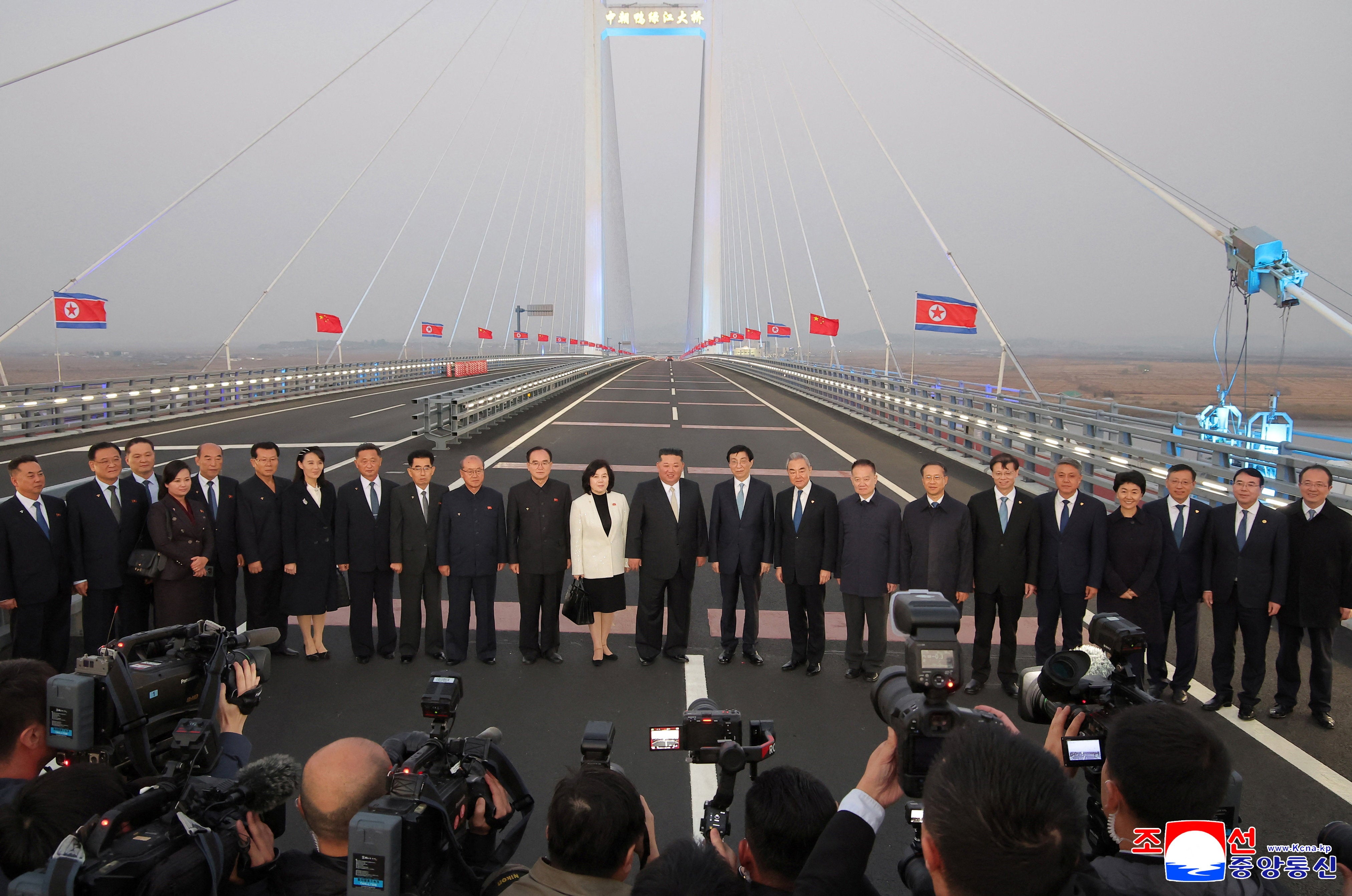 North Korean leader Kim Jong Un, Chinese People's Political Consultative Conference (CPPCC) Chairman Wang Huning, Chinese Foreign Minister Wang Yi, and North Korean Foreign Minister Choe Son Hui pose for a photograph with officials on the New Yalu River Bridge linking Dandong, Chin