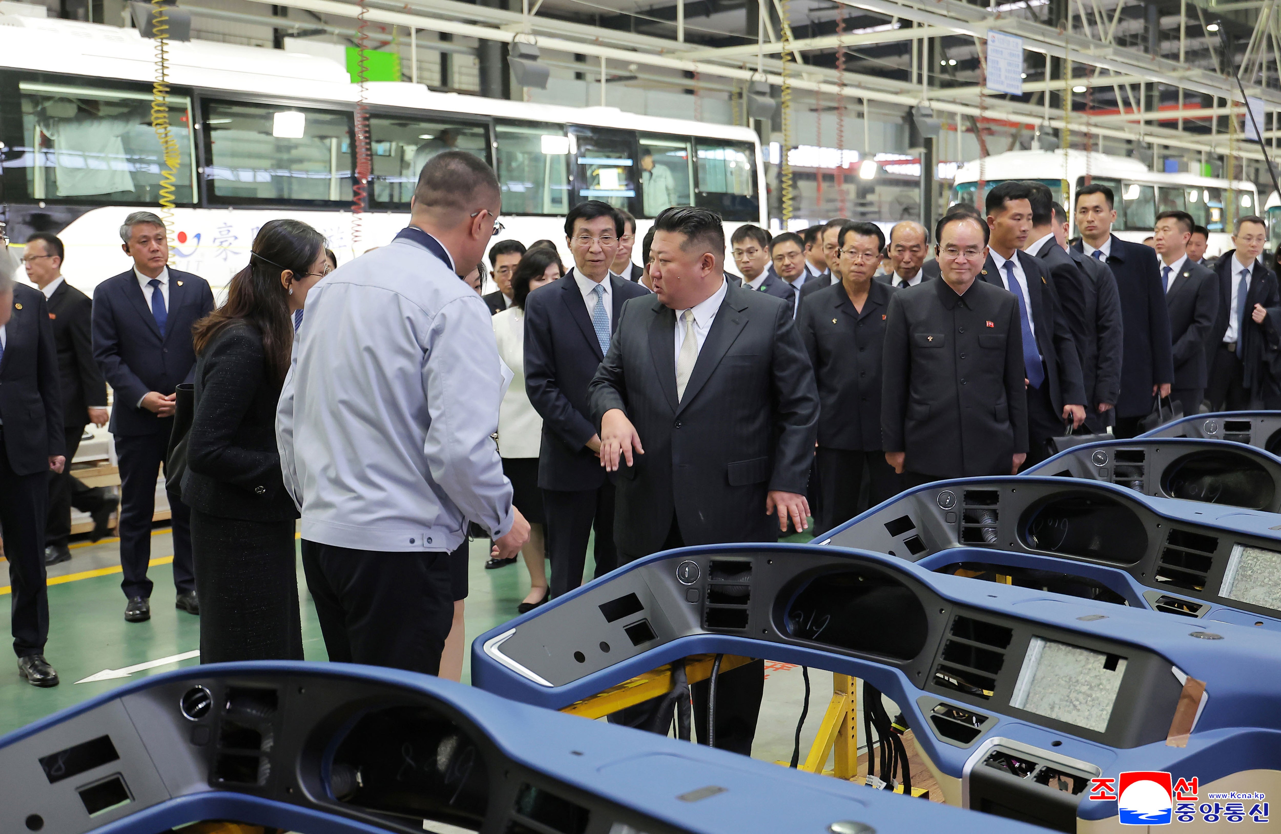 In this photo provided by the North Korean government, its leader Kim Jong Un, front right, tours a bus factory in Dandong, China Saturday, Oct. 24, 2026