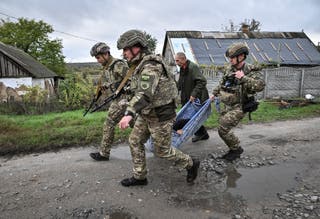 File: Police officers evacuate a resident from the frontline rural settlement Komyshuvakha, amid Russia's attack on Ukraine, in Zaporizhzhia region, Ukraine 19 October 2026