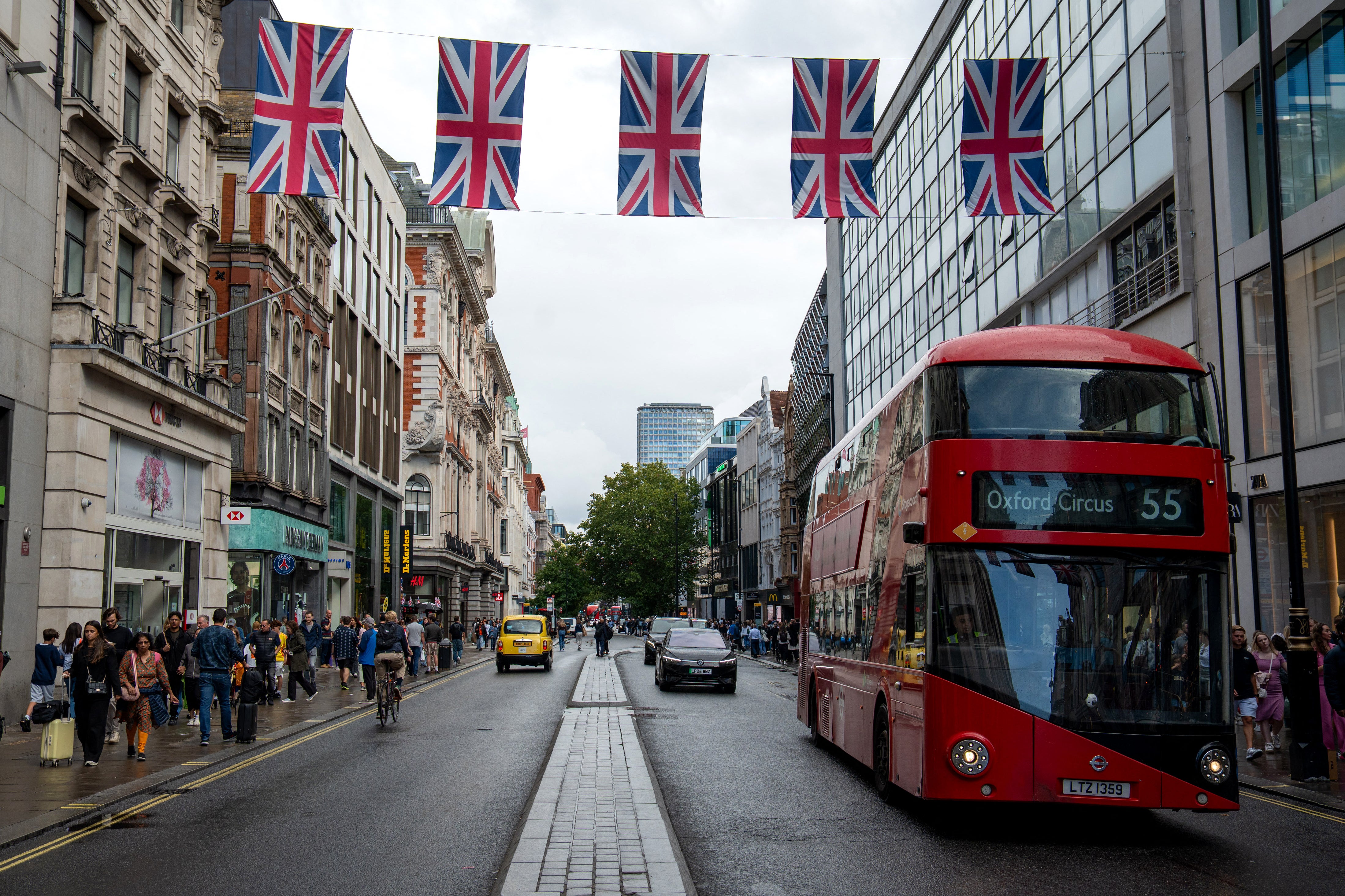 Pedestrians walk on the pavement beside vehicles being driven on Oxford Street in central London on September 1, 2025. Oxford street