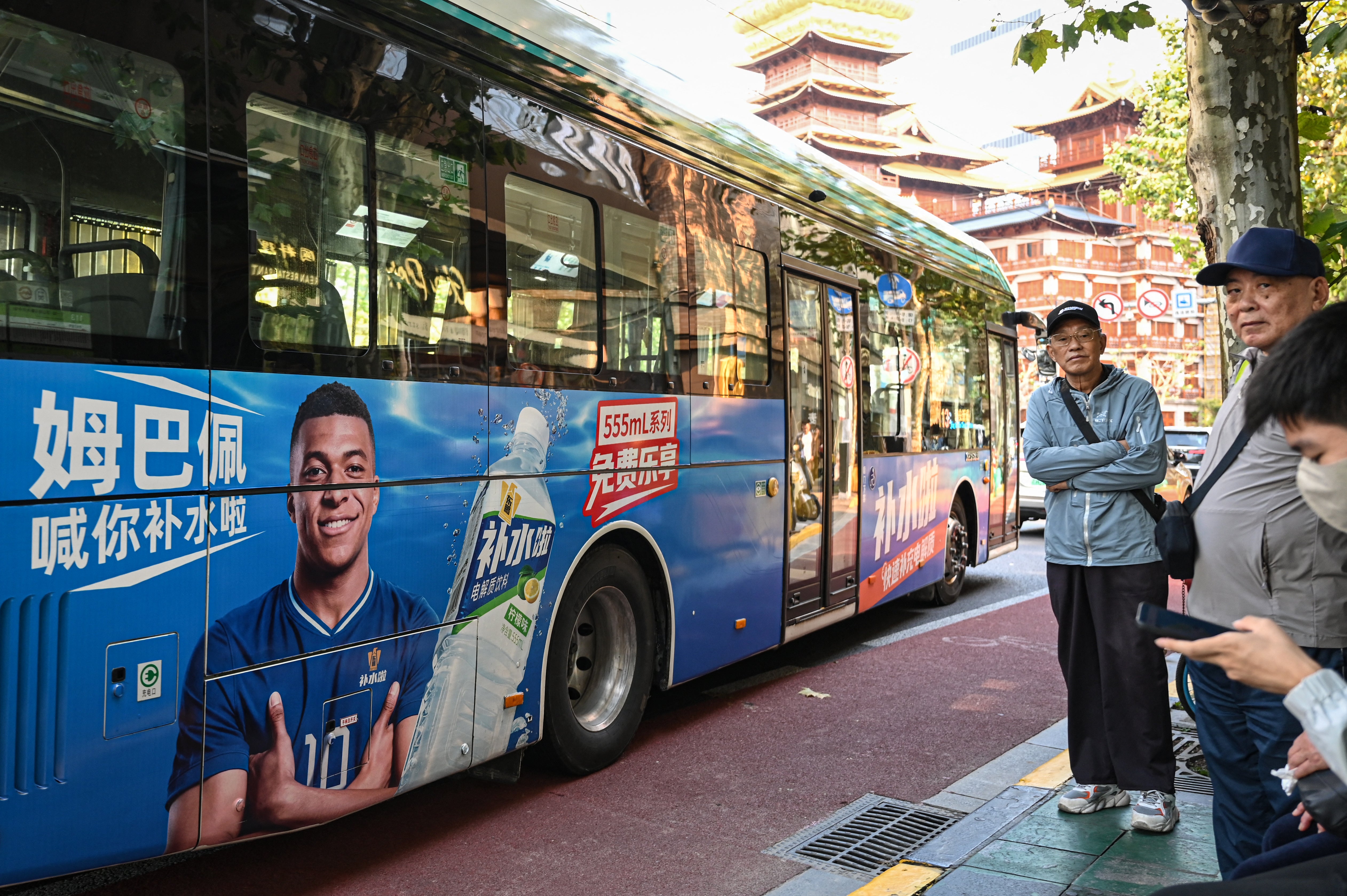 A bus featuring French football star Kylian Mbappe for Dongpeng Beverage Group's 'Bushuila' electrolyte drink is seen on a street in Shanghai on October 27,