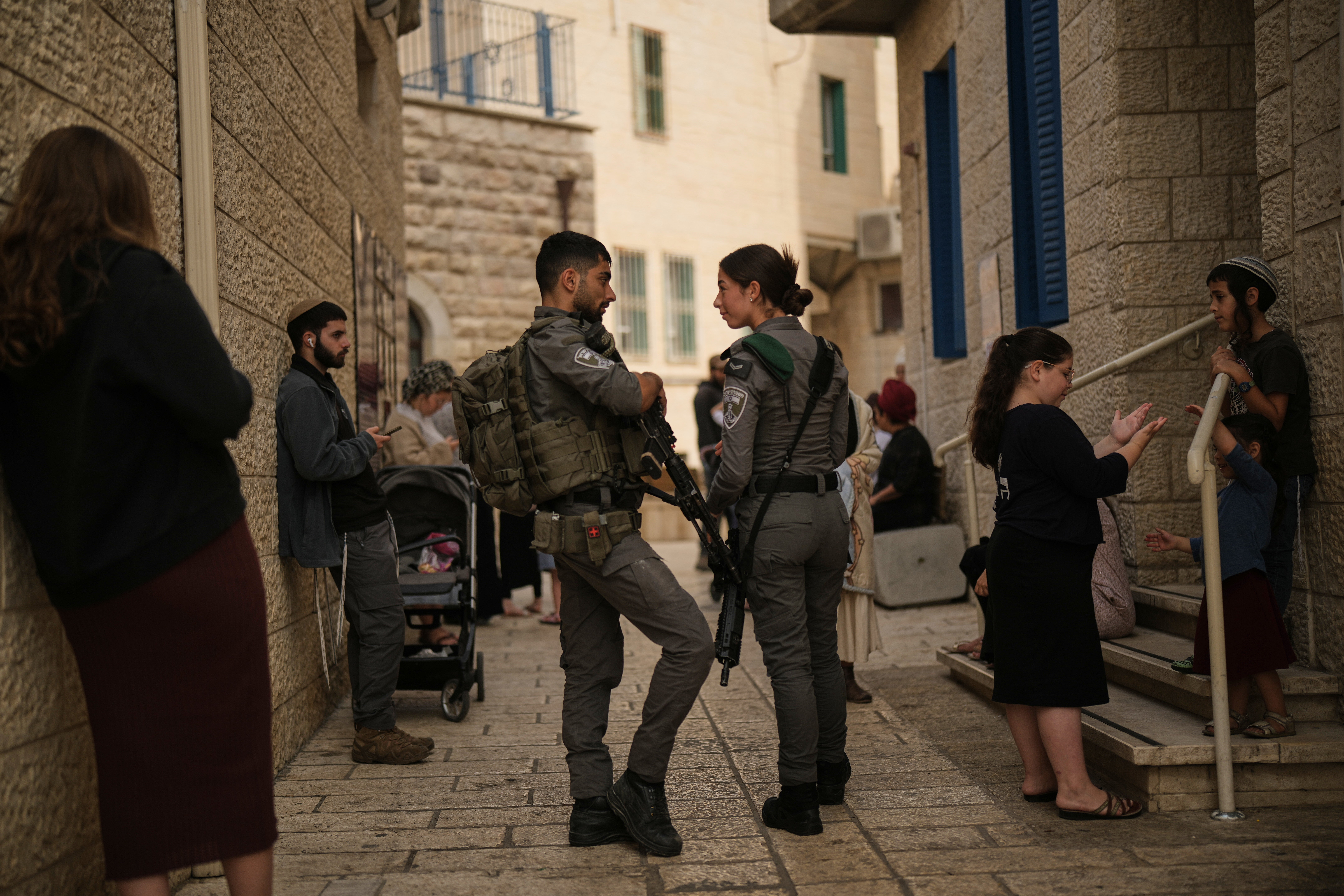 Israeli settlers and border police officers line up to vote outside a polling station in Hebron, in the West Bank
