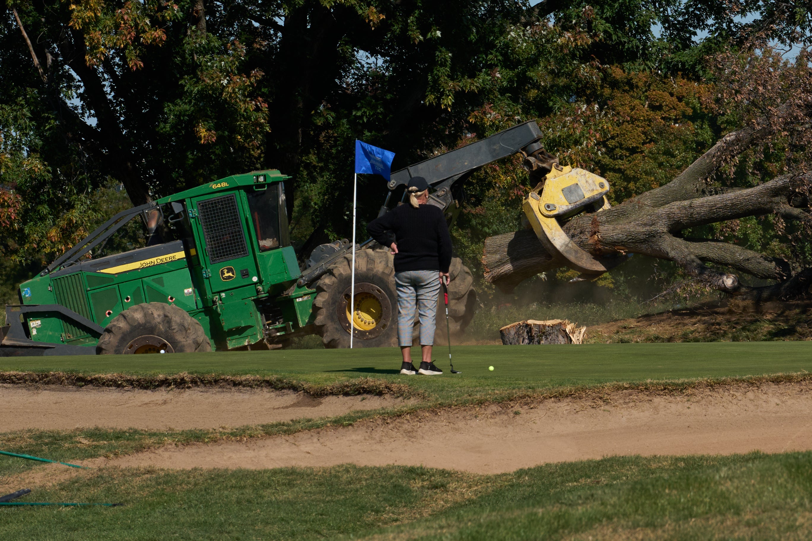 A golfer watches as trees are removed at East Potomac Park Golf Course, Monday, Oct. 26, 2026, in Washington